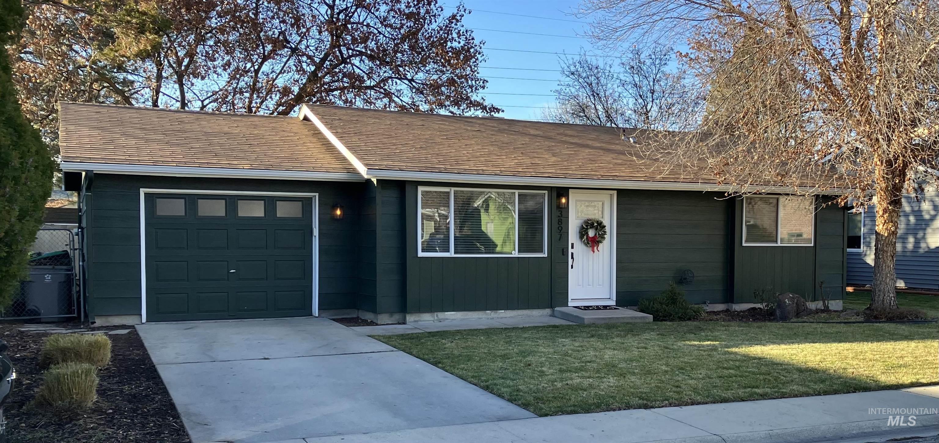 Ranch-style home with driveway, a front lawn, an attached garage, and a shingled roof