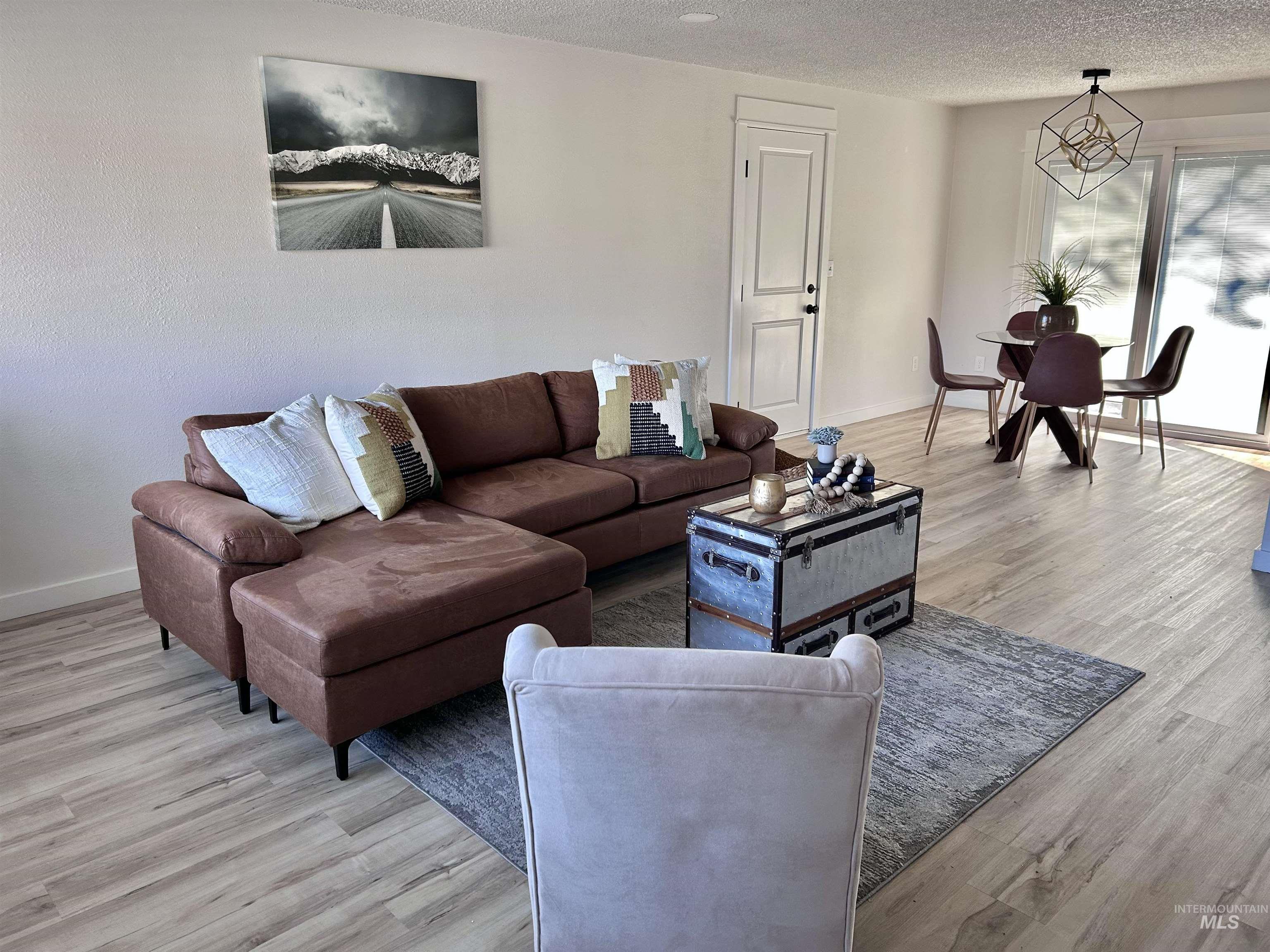 Living area featuring a textured ceiling, light wood-type flooring, and a chandelier