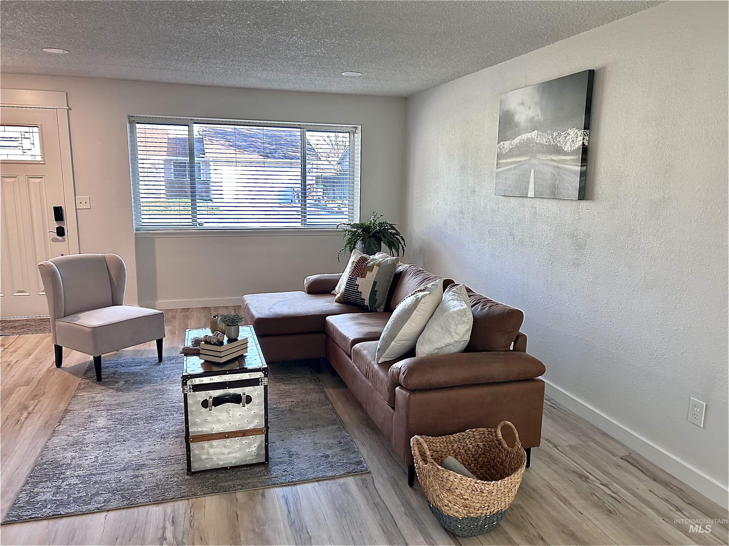 Living area with a textured ceiling, light wood-style floors, and a textured wall