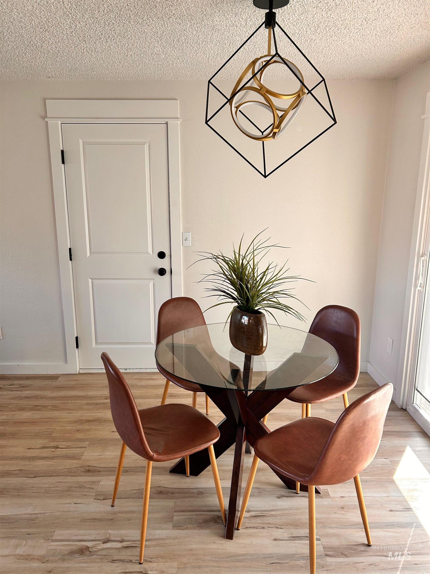 Dining area with a textured ceiling and light wood-style floors