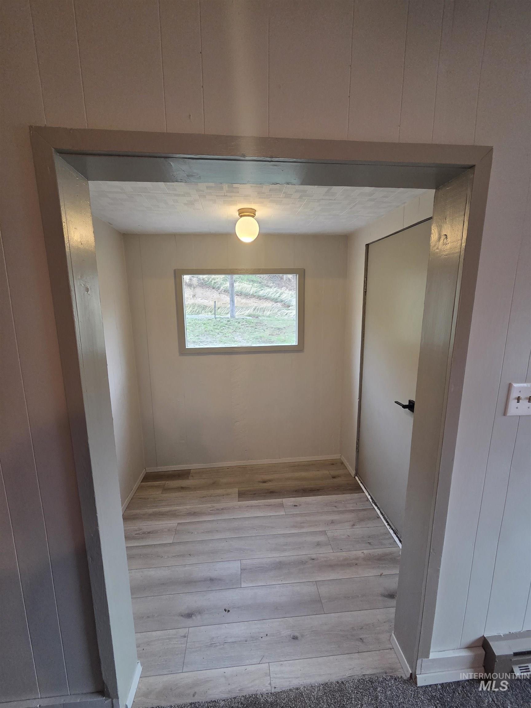 Corridor featuring light wood finished floors and wood walls