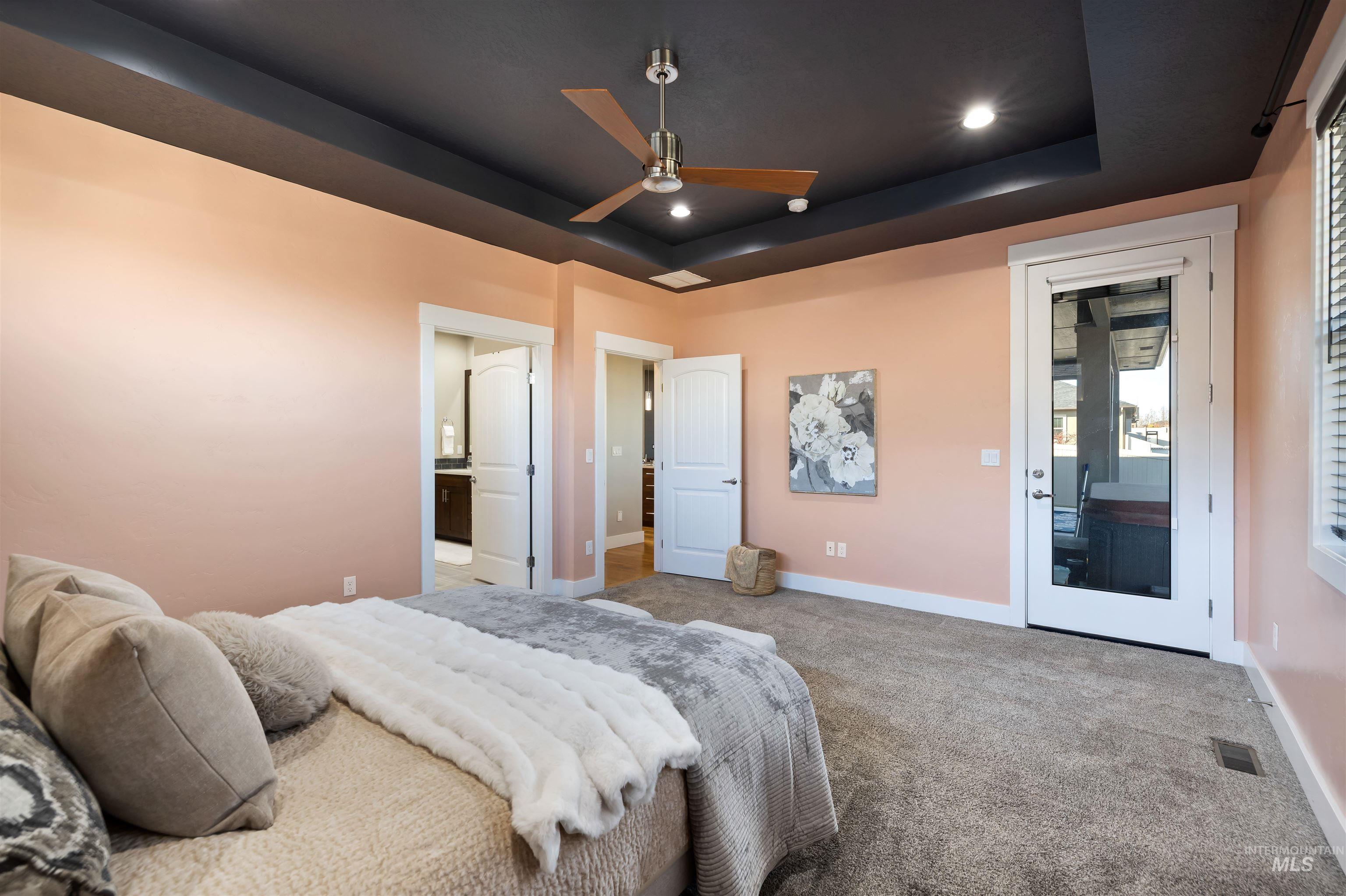 Bedroom with a tray ceiling, ceiling fan, carpet flooring, recessed lighting, and ensuite bathroom