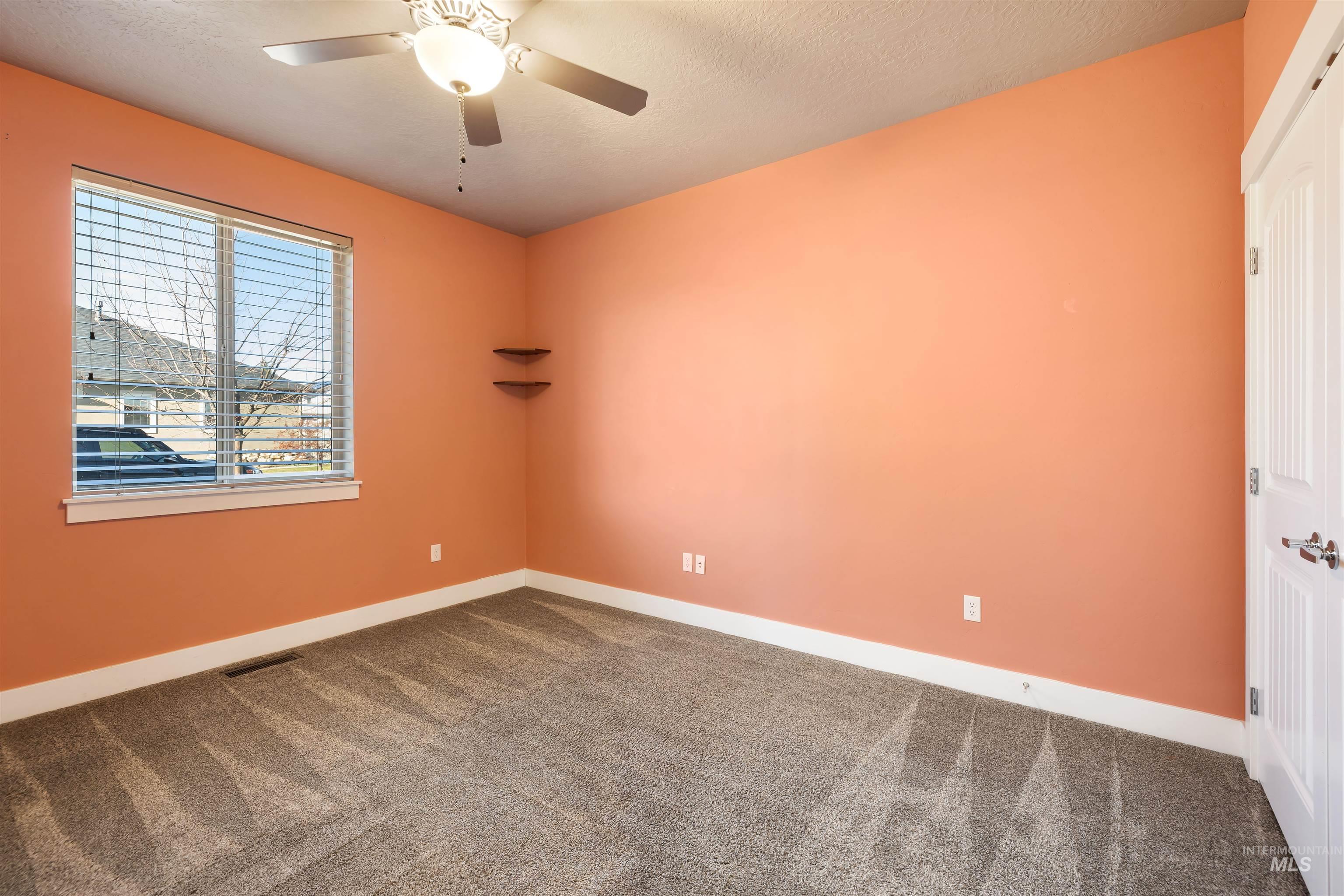 Carpeted empty room featuring a textured ceiling and ceiling fan