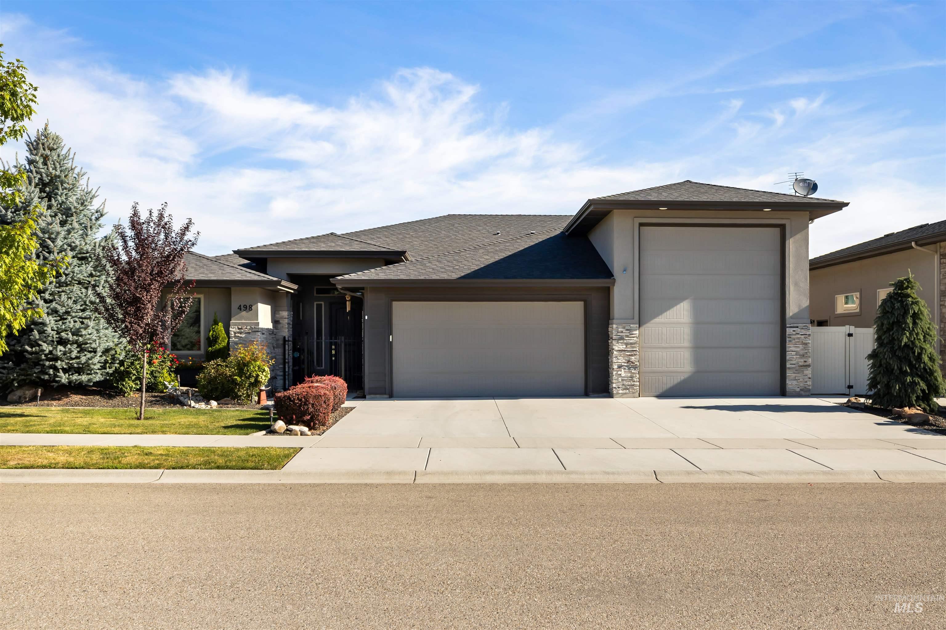 Prairie-style house featuring stone siding, a garage, roof with shingles, concrete driveway, and stucco siding