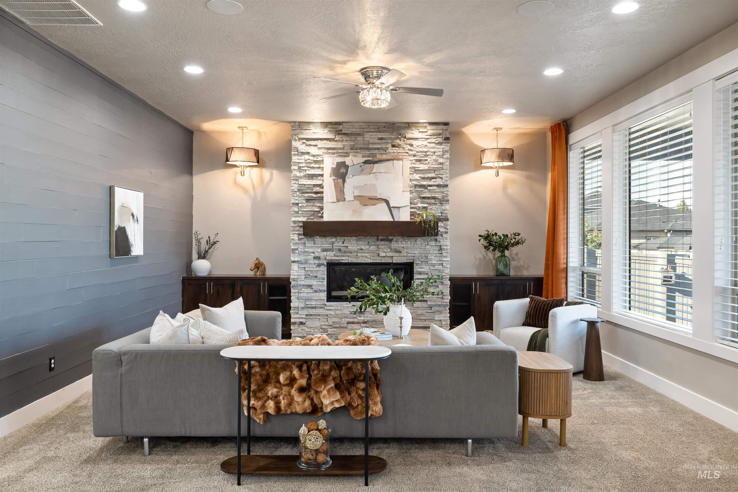 Living area with a textured ceiling, a stone fireplace, carpet flooring, a ceiling fan, and recessed lighting