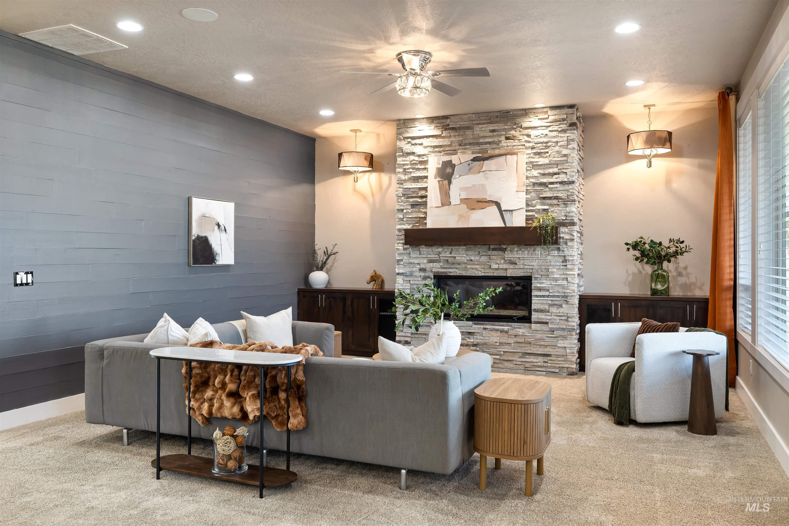Carpeted living area with recessed lighting, a stone fireplace, a ceiling fan, and wooden walls