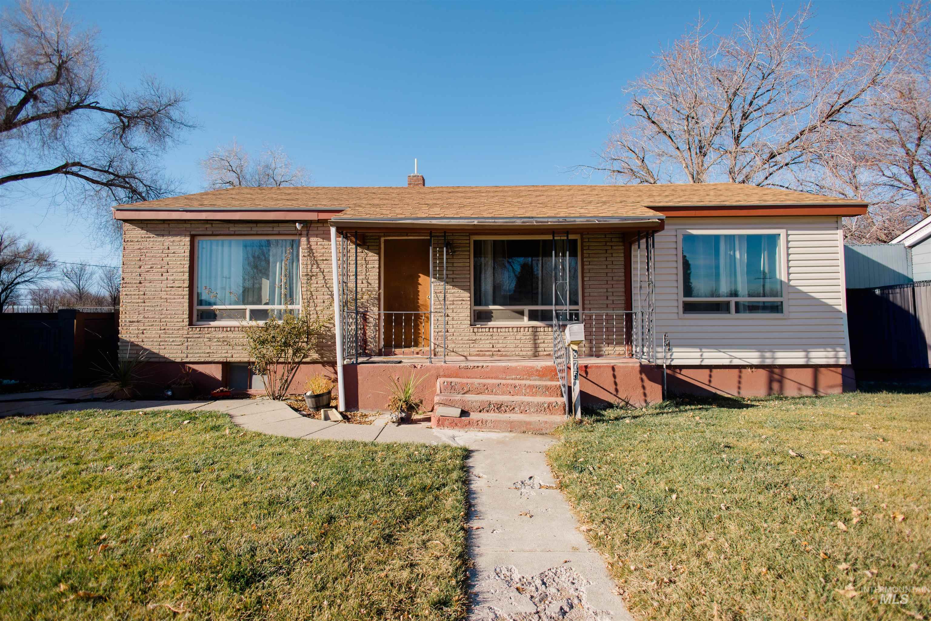 View of front of home featuring covered porch, a front yard, brick siding, and roof with shingles