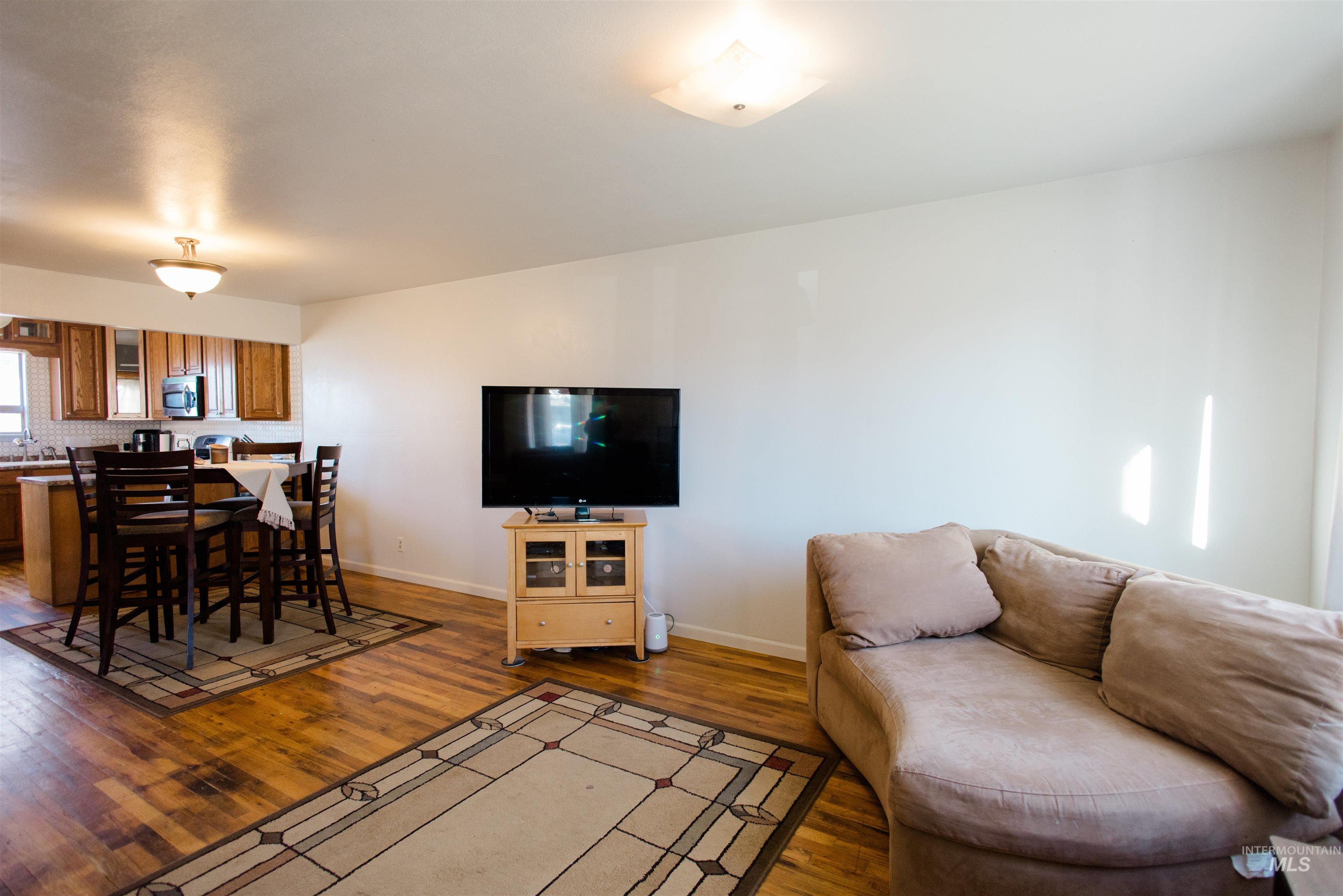 Living area featuring dark wood-style flooring and baseboards
