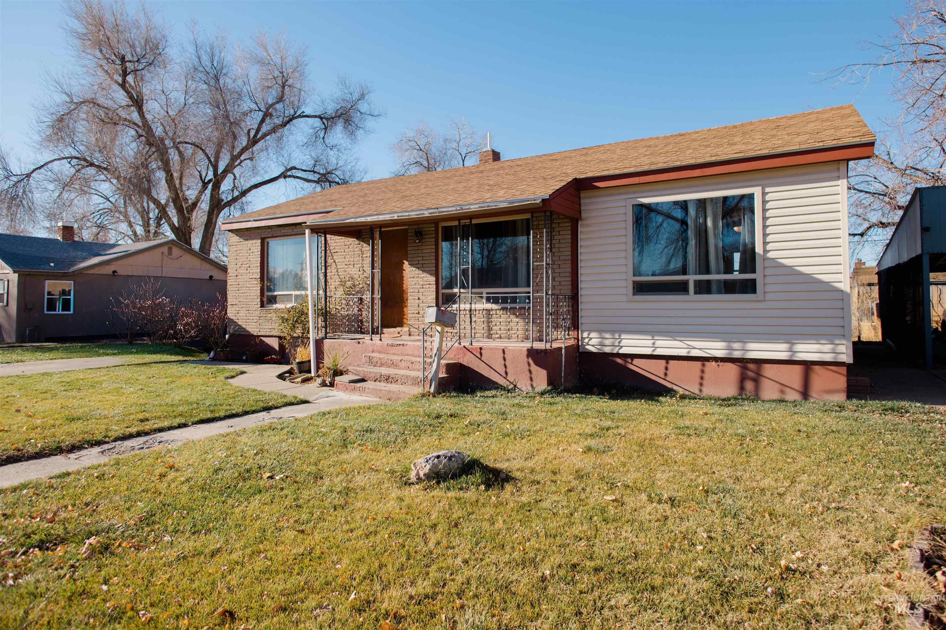 Bungalow featuring a front lawn, a porch, a chimney, and brick siding