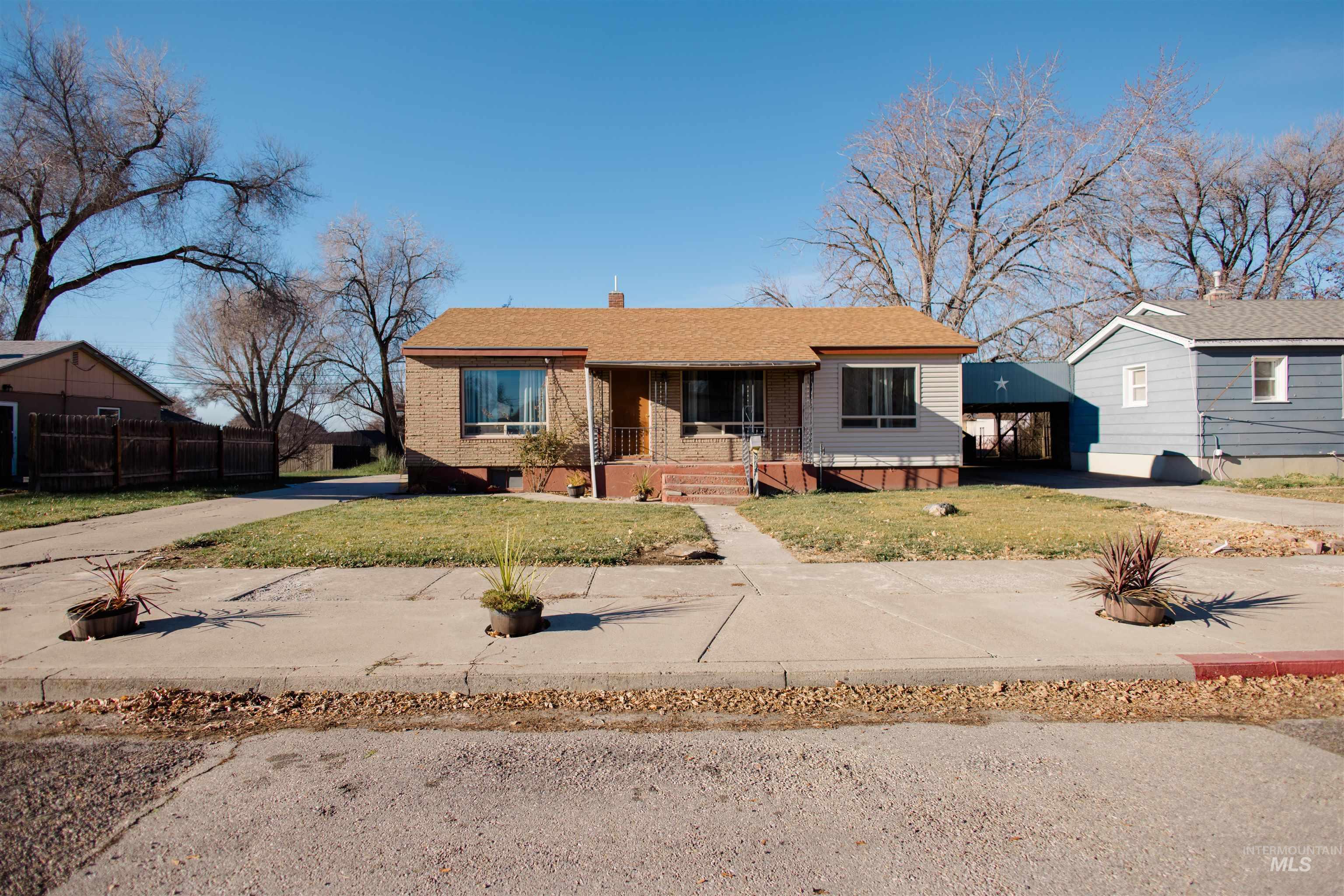 View of front of property with covered porch, driveway, a chimney, a front lawn, and brick siding