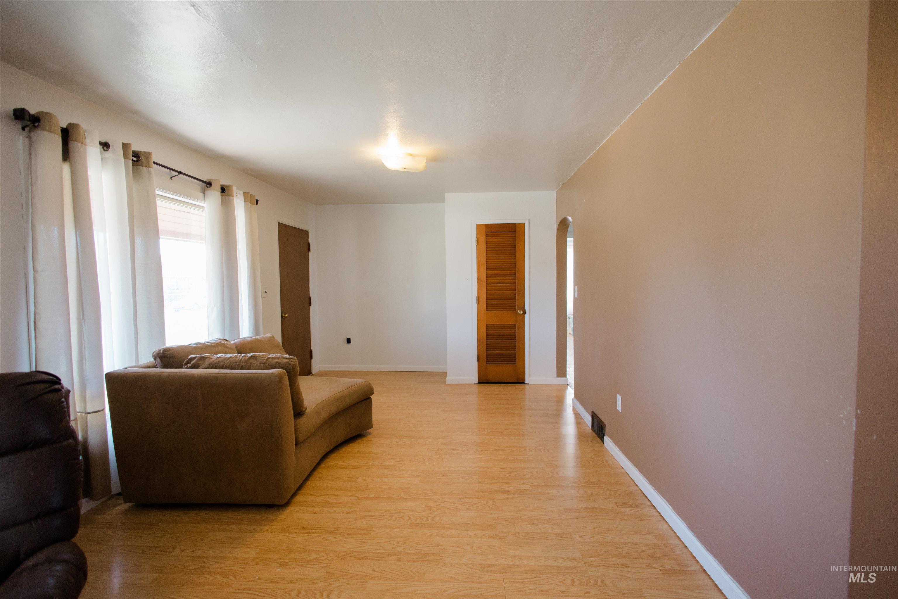 Living area featuring arched walkways and light wood-style floors
