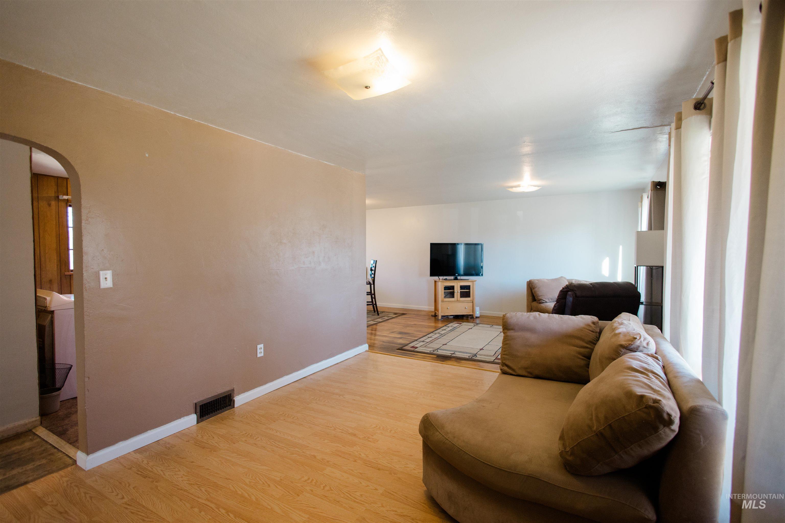Living area featuring arched walkways and light wood finished floors