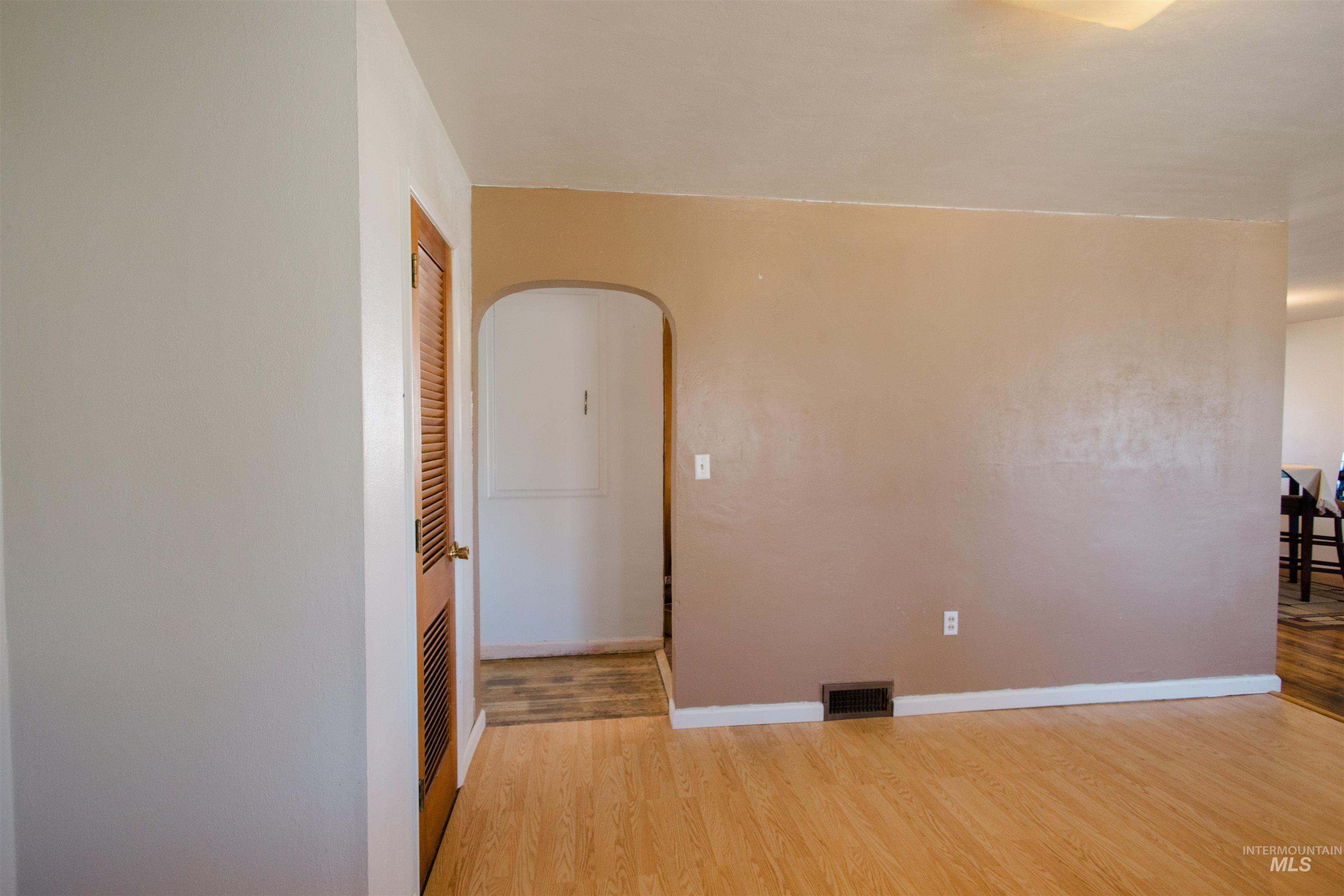 Unfurnished room with arched walkways and light wood finished floors