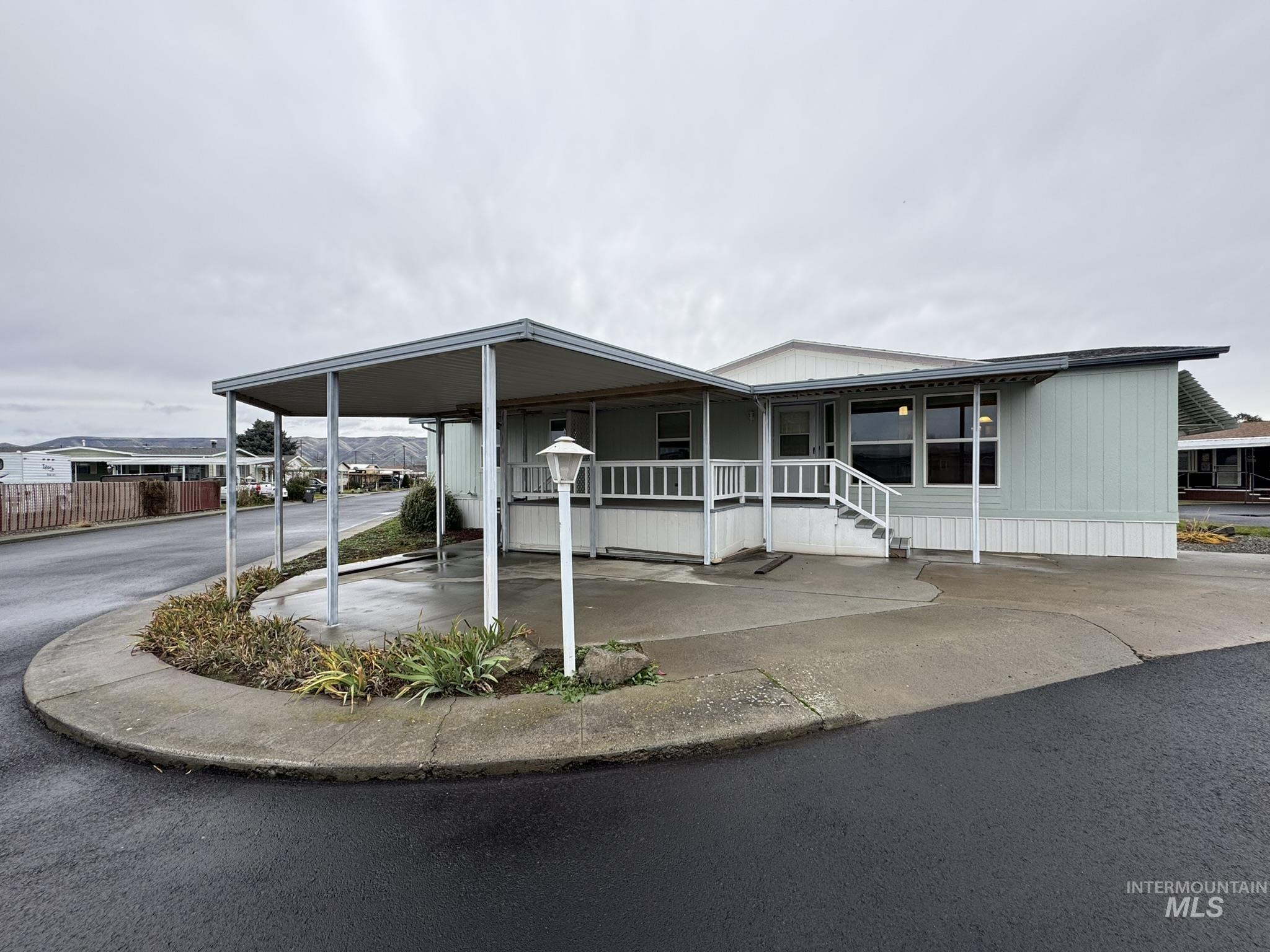 Manufactured / mobile home with a porch, a carport, and driveway