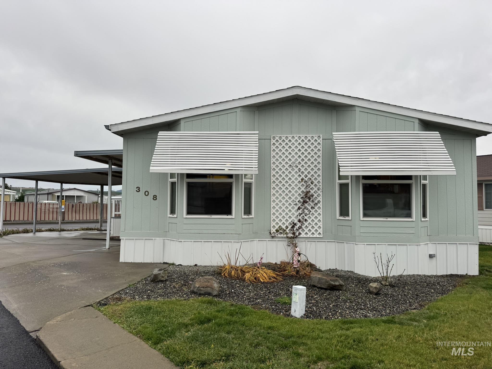 View of side of property with an attached carport and concrete driveway