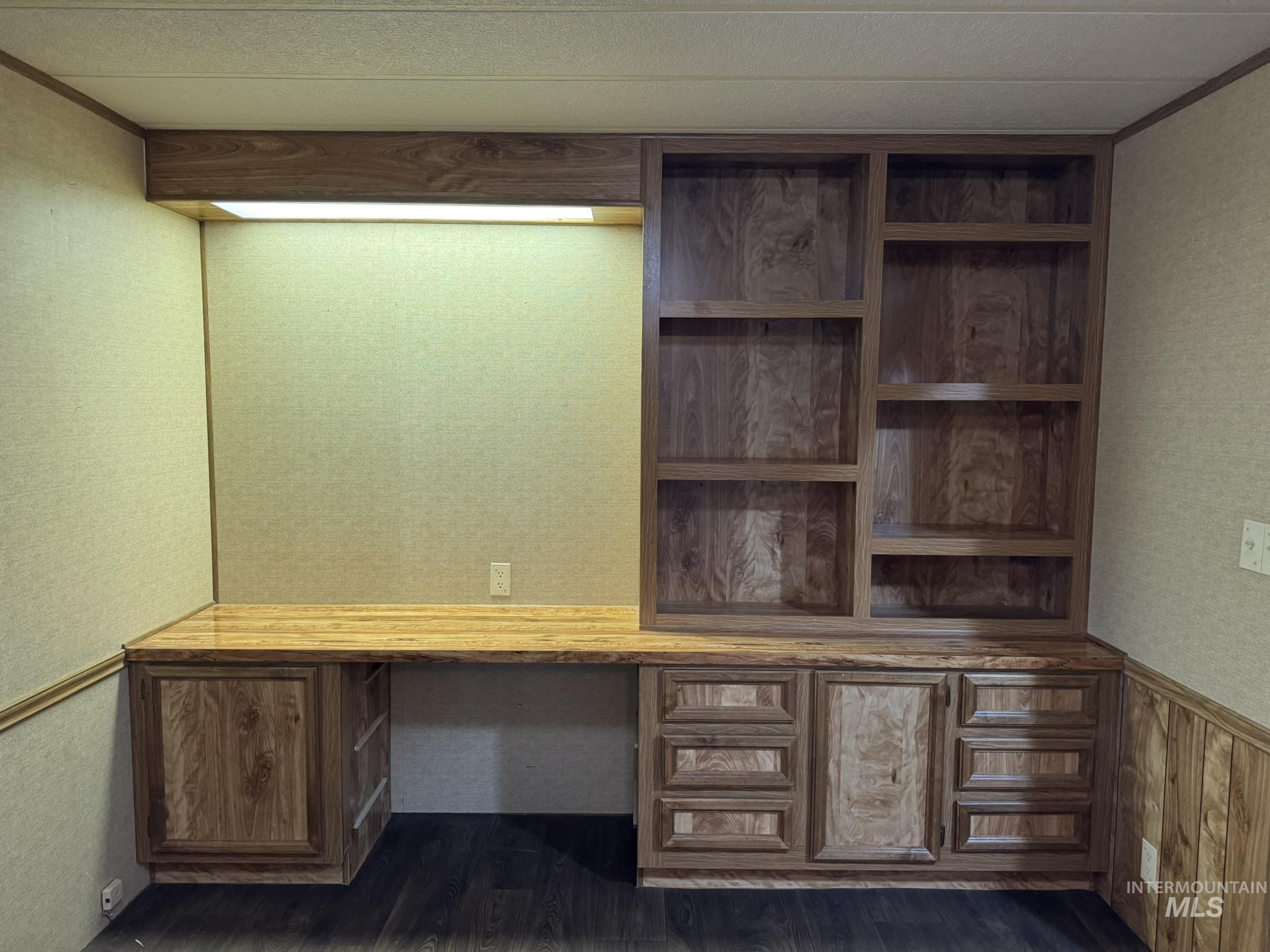 Unfurnished office with wallpapered walls, wainscoting, and dark wood finished floors