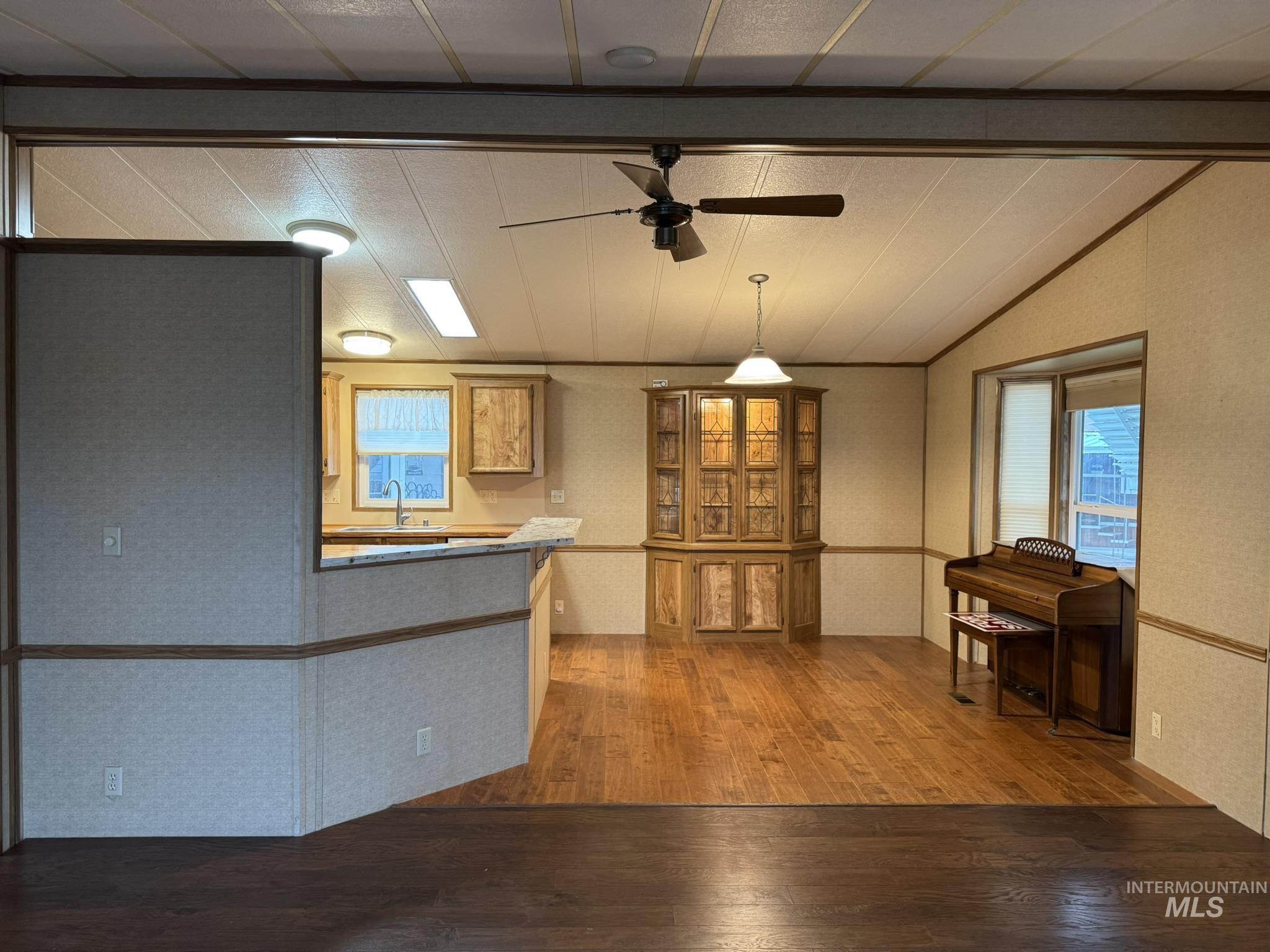 Unfurnished dining area featuring hardwood / wood-style flooring, a ceiling fan, and vaulted ceiling