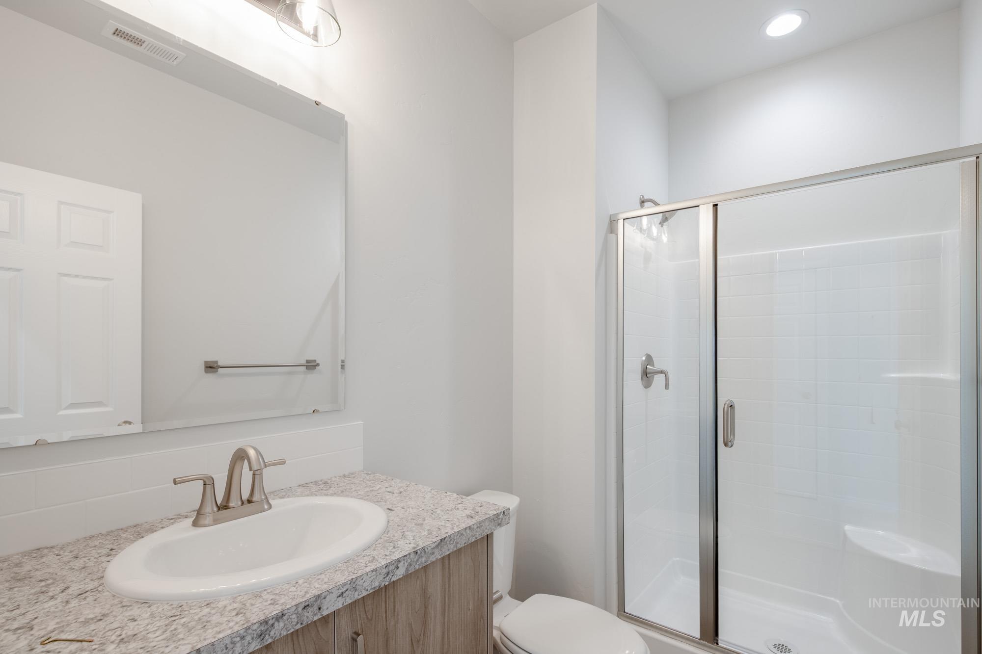 Full bathroom with a shower stall, vanity, tasteful backsplash, and recessed lighting