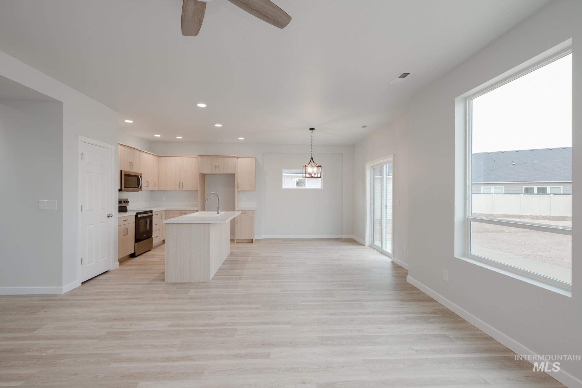 Kitchen featuring light countertops, stainless steel appliances, light wood-type flooring, recessed lighting, and a center island with sink