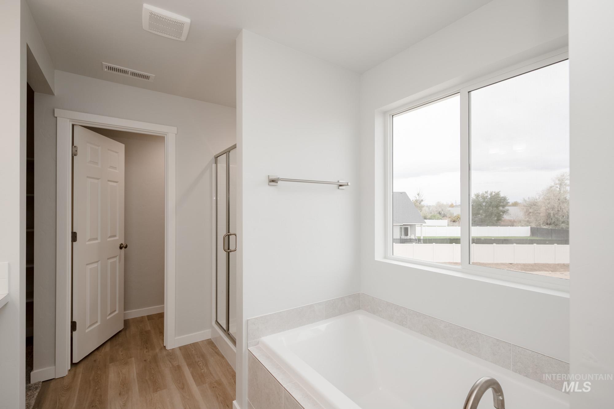 Full bathroom featuring a bath, a shower stall, light wood-style floors, and vanity