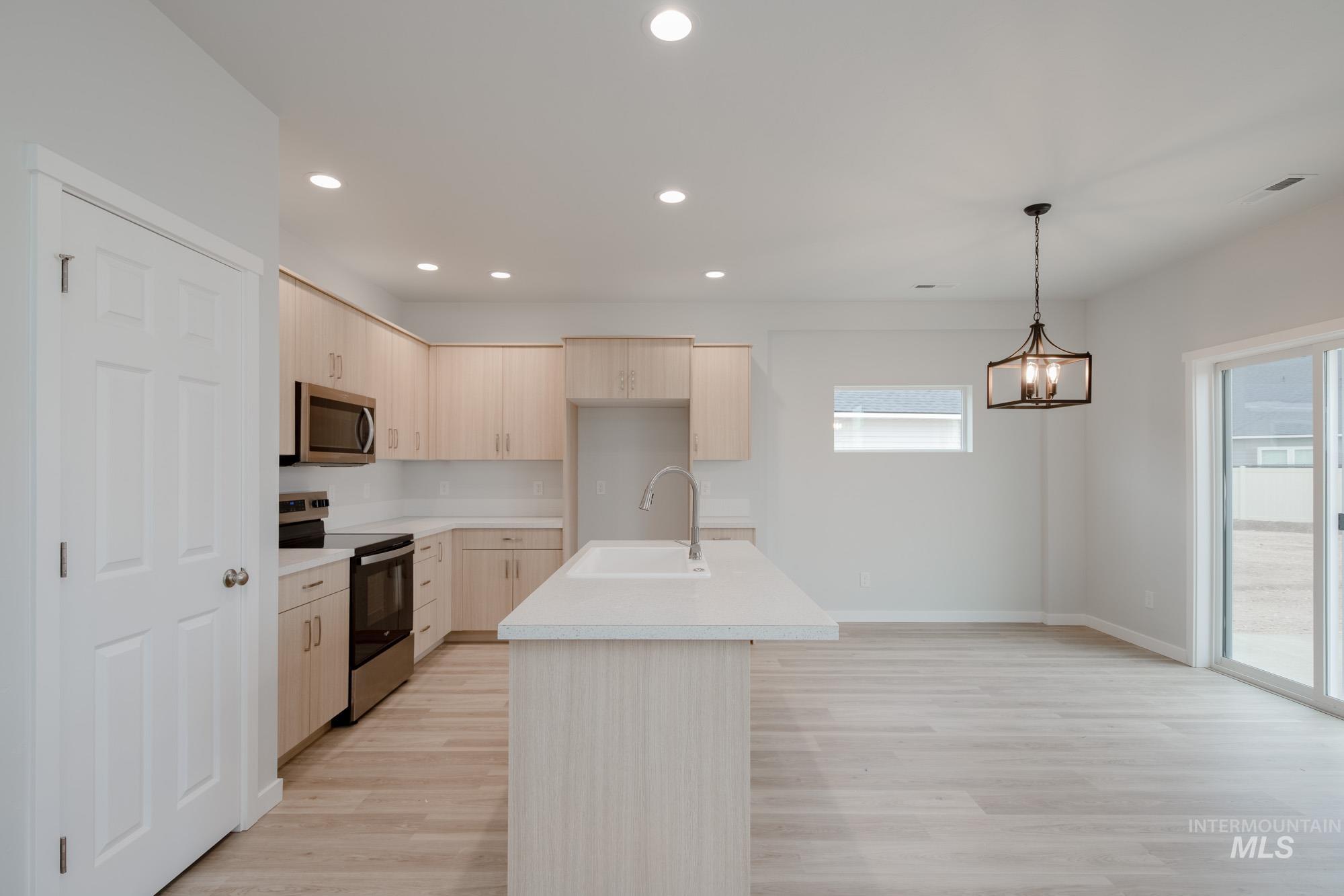 Kitchen featuring stainless steel appliances, light countertops, recessed lighting, light brown cabinets, and light wood finished floors