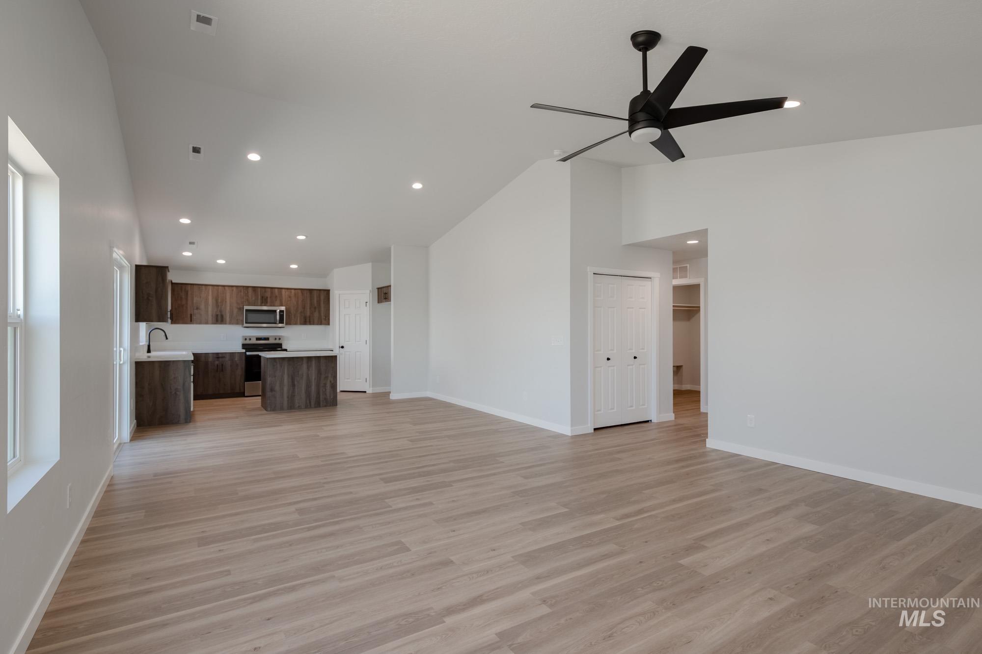Unfurnished living room with light wood-style flooring, recessed lighting, high vaulted ceiling, and a ceiling fan