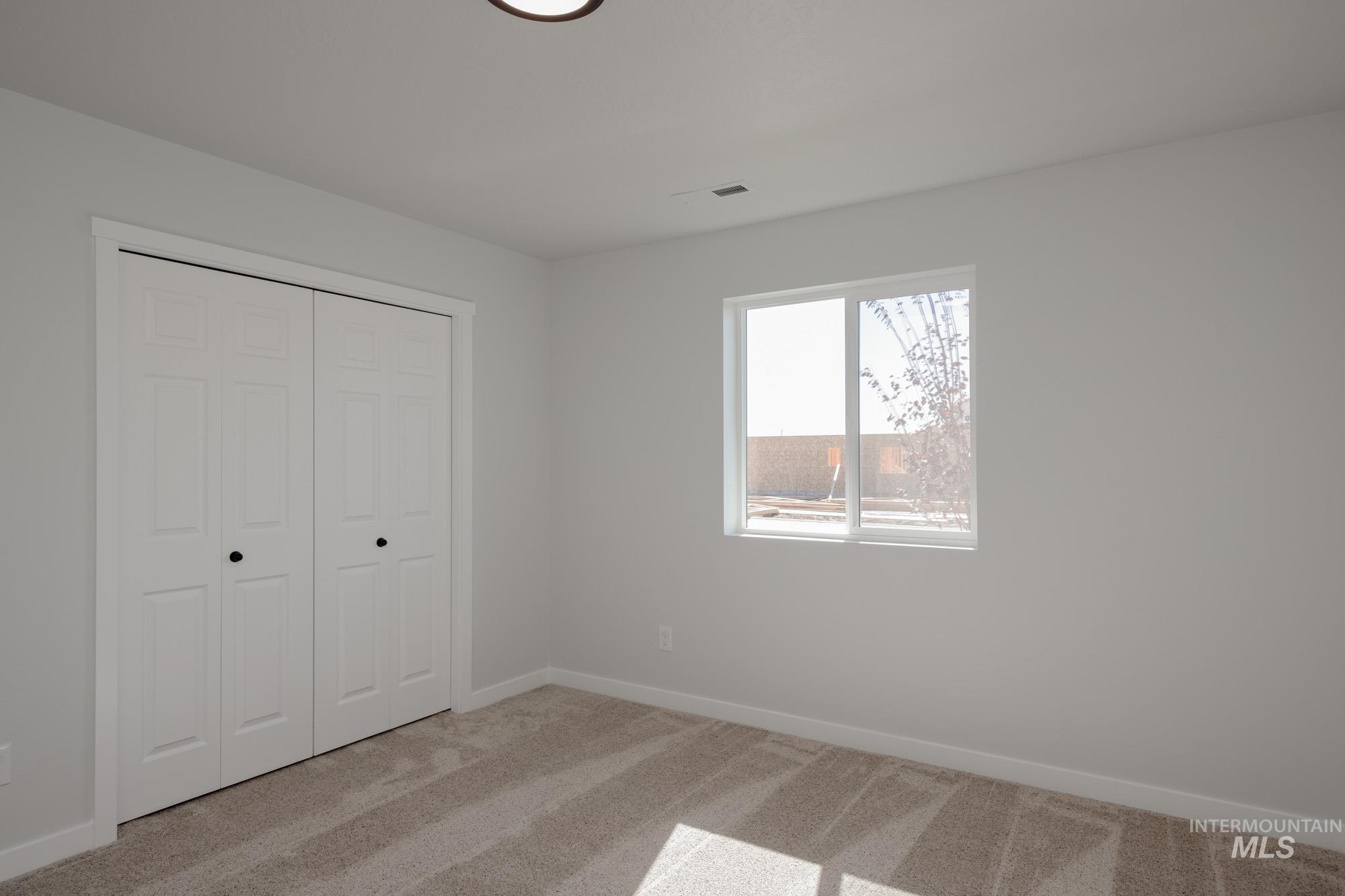 Unfurnished bedroom featuring light carpet and a closet