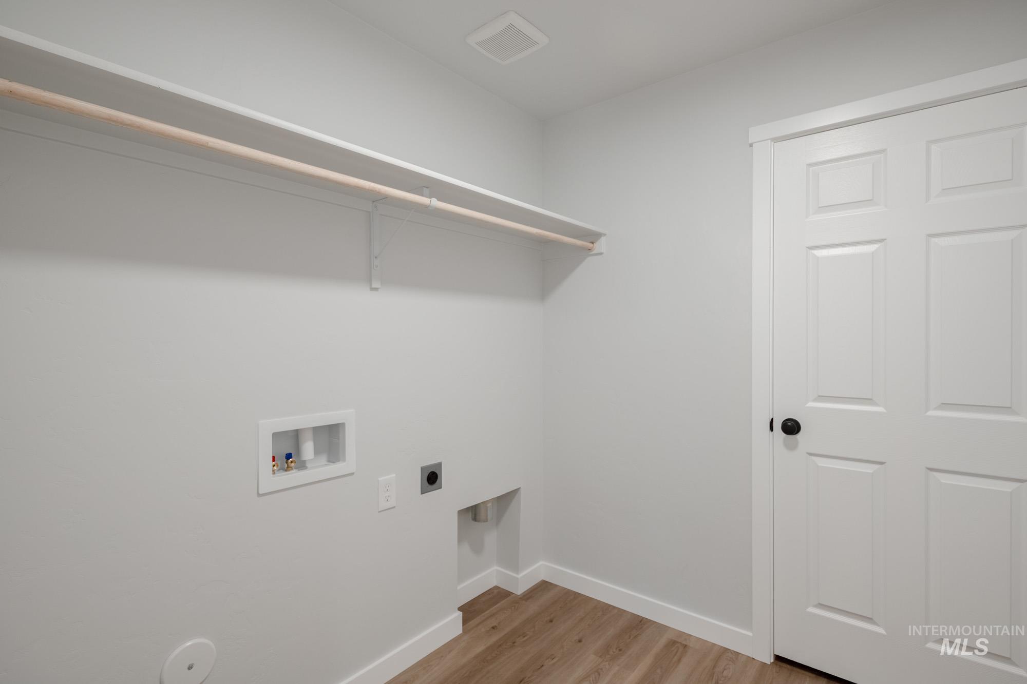 Laundry room with light wood-type flooring, hookup for an electric dryer, and hookup for a washing machine