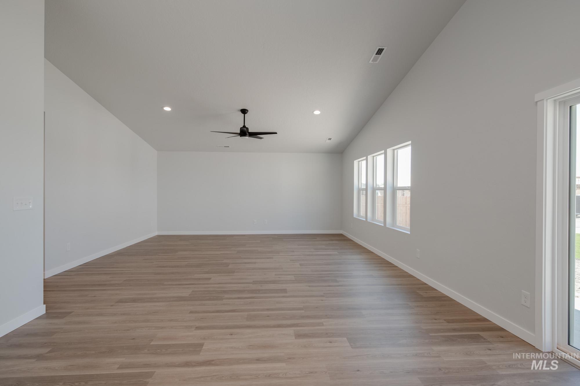 Spare room featuring light wood finished floors, lofted ceiling, recessed lighting, and a ceiling fan