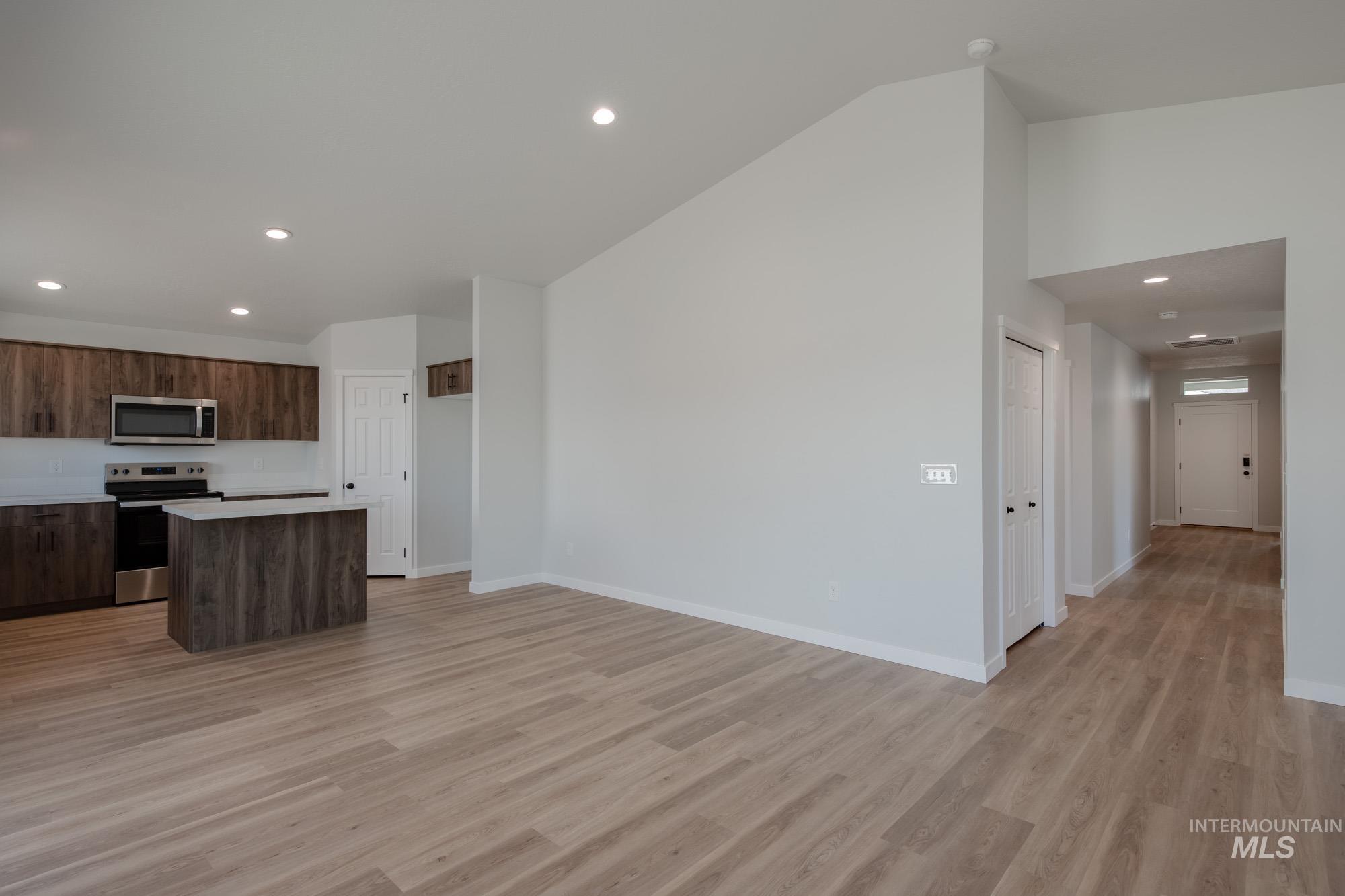 Kitchen featuring recessed lighting, a kitchen island, light countertops, stainless steel appliances, and light wood-type flooring
