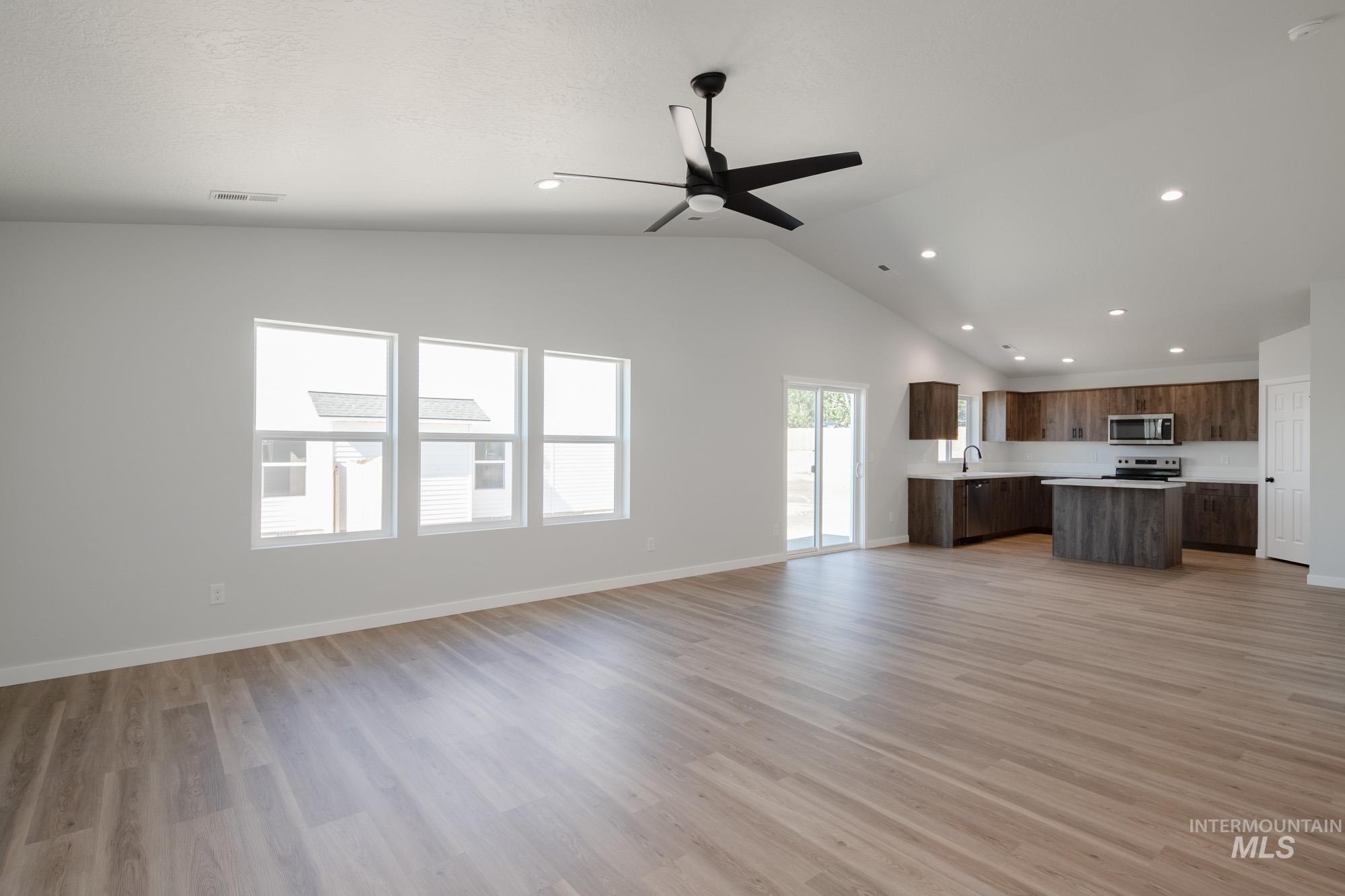Unfurnished living room featuring light wood-style flooring, a ceiling fan, recessed lighting, and high vaulted ceiling