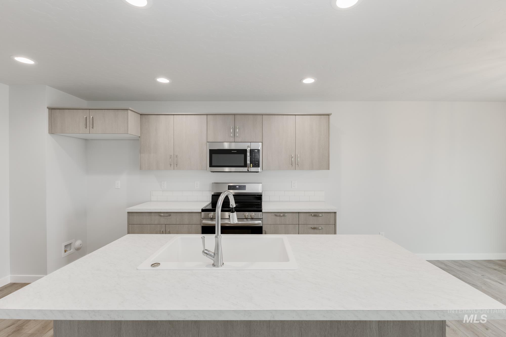 Kitchen featuring light wood-style flooring, light brown cabinetry, stainless steel appliances, light countertops, and recessed lighting