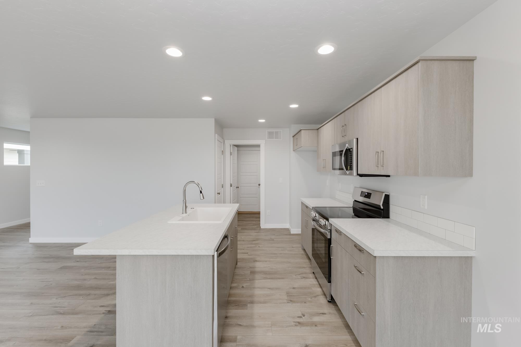 Kitchen with light brown cabinetry, modern cabinets, light countertops, and recessed lighting