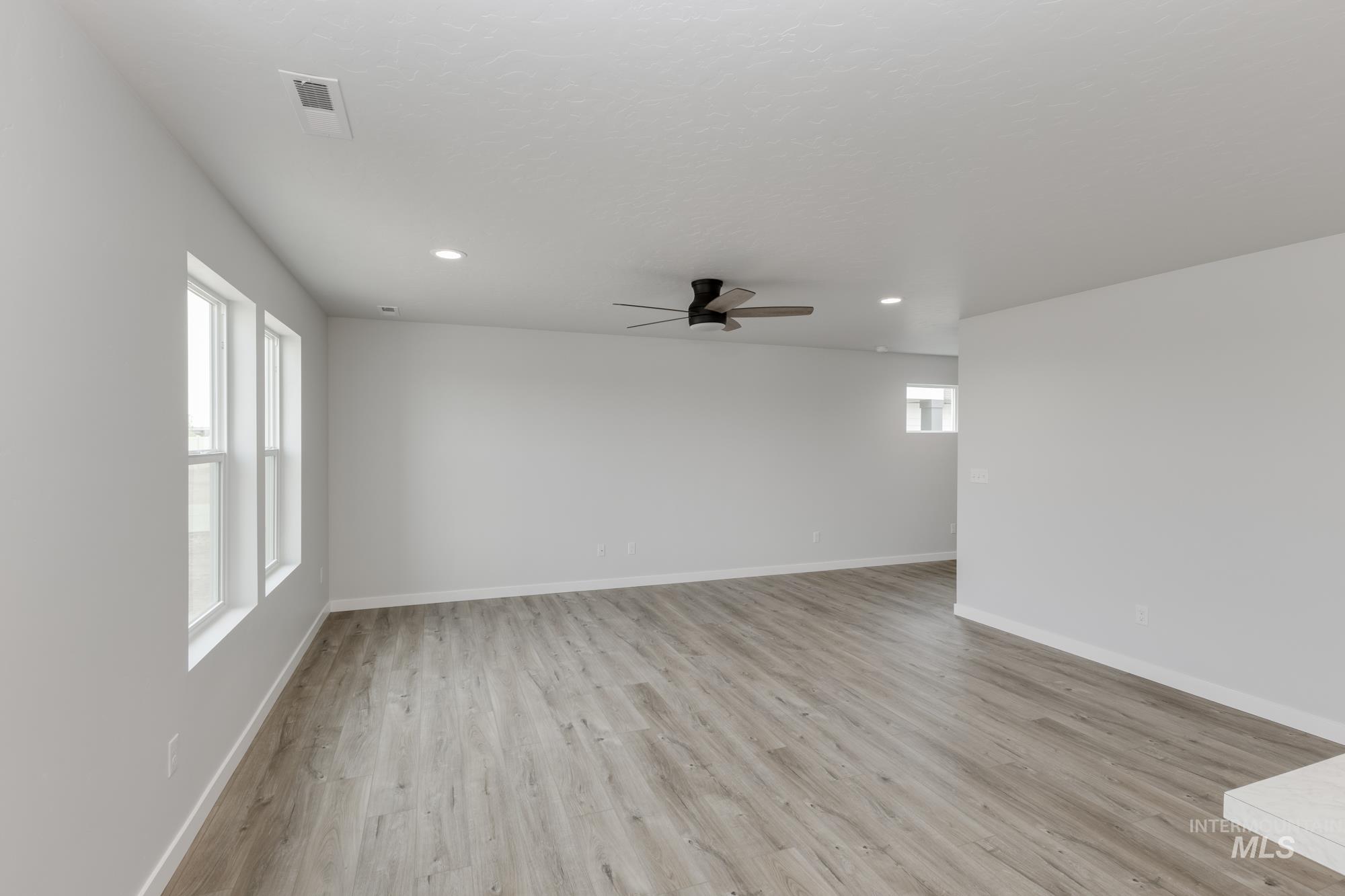 Empty room featuring light wood-type flooring, ceiling fan, and recessed lighting