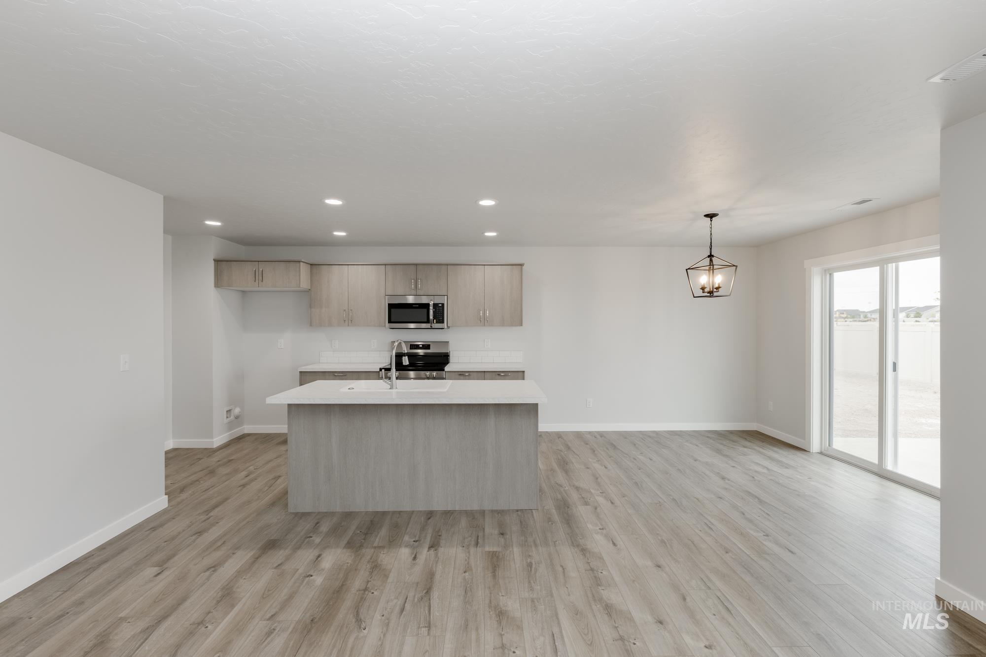 Kitchen with a center island with sink, recessed lighting, pendant lighting, light wood-type flooring, and appliances with stainless steel finishes