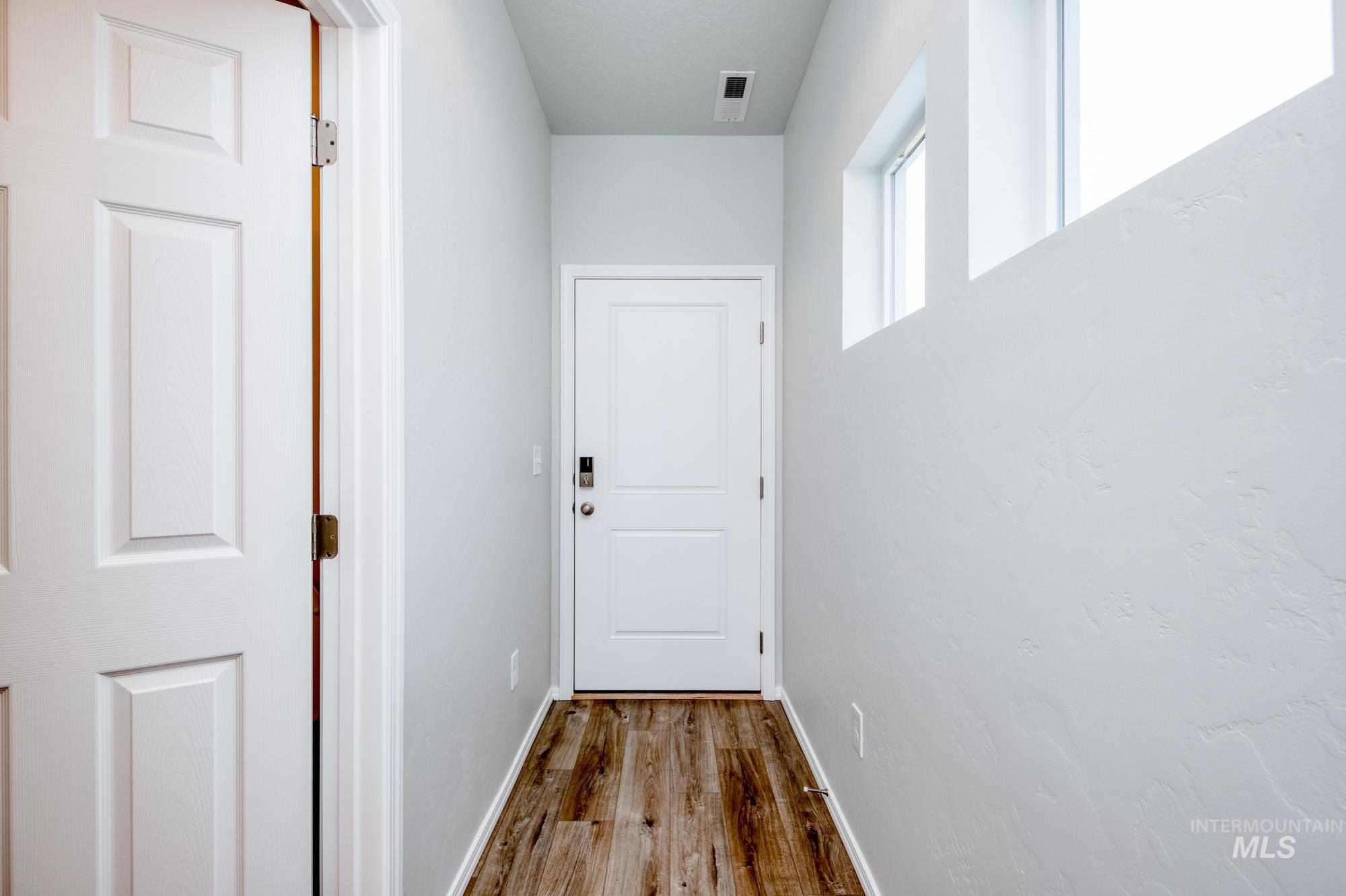 Doorway featuring baseboards and wood finished floors