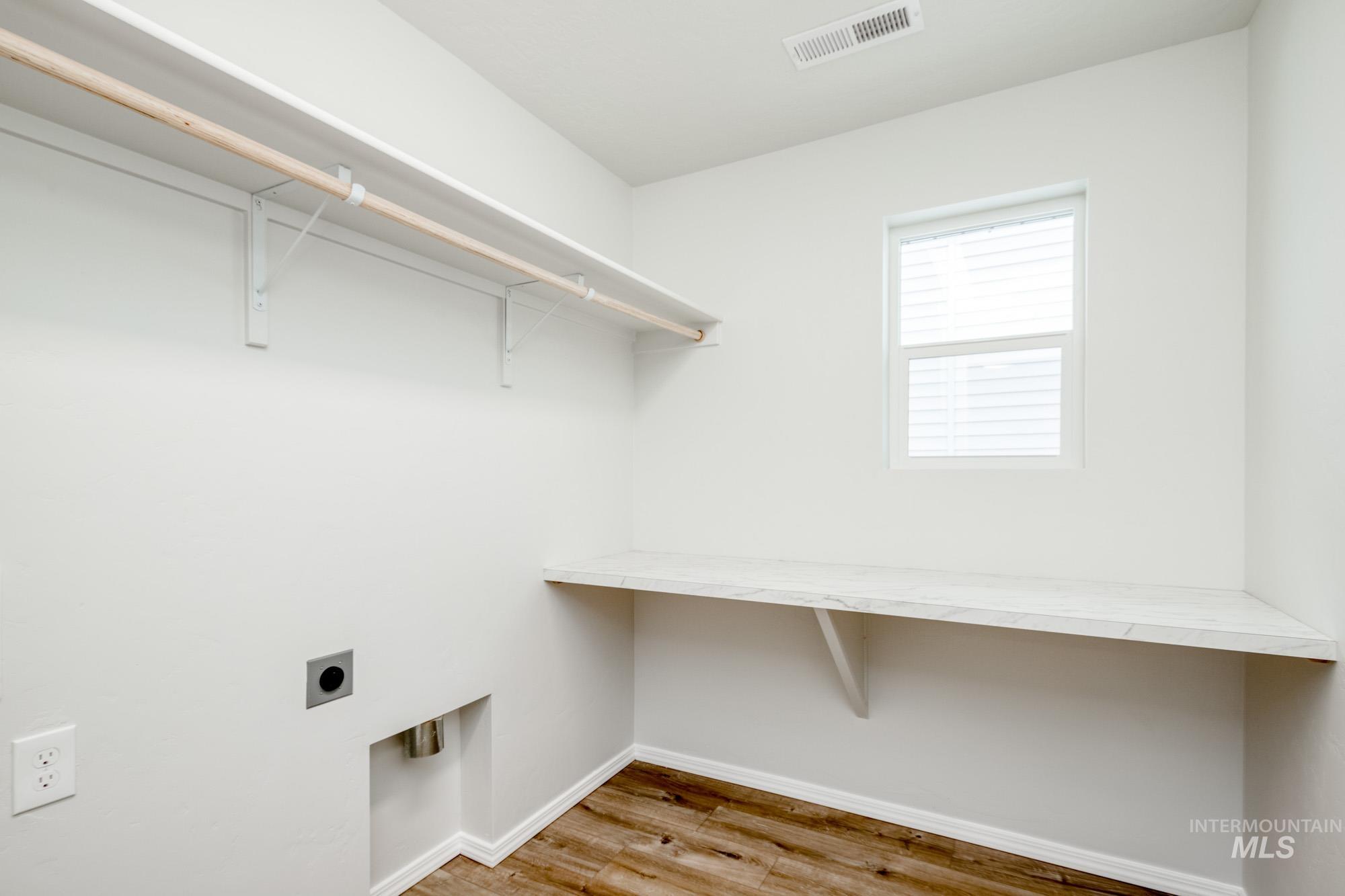 Laundry area with light wood-style floors and electric dryer hookup