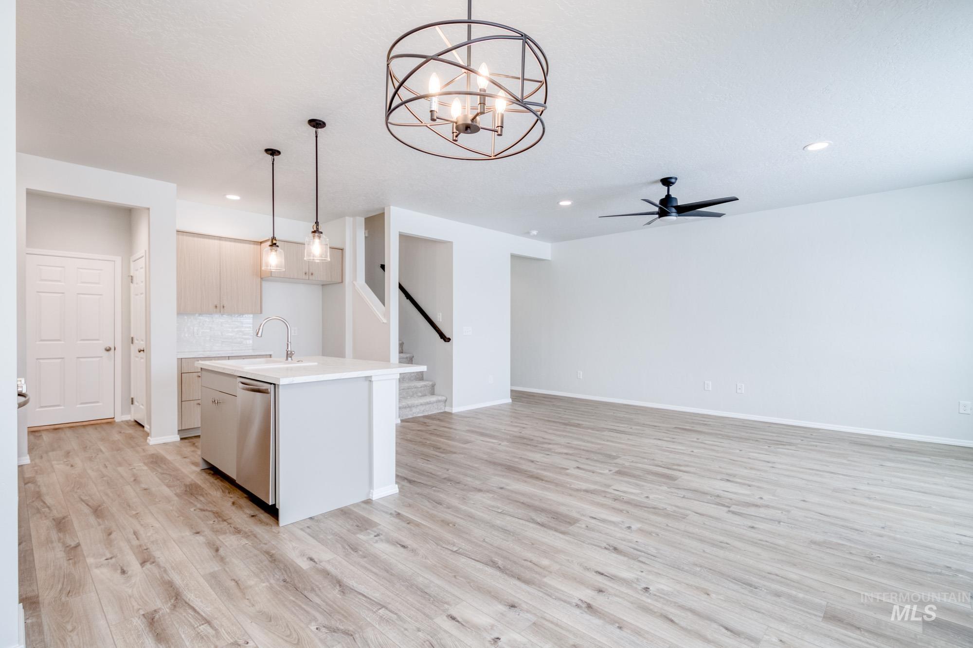 Kitchen featuring hanging light fixtures, a center island with sink, ceiling fan, backsplash, and a chandelier
