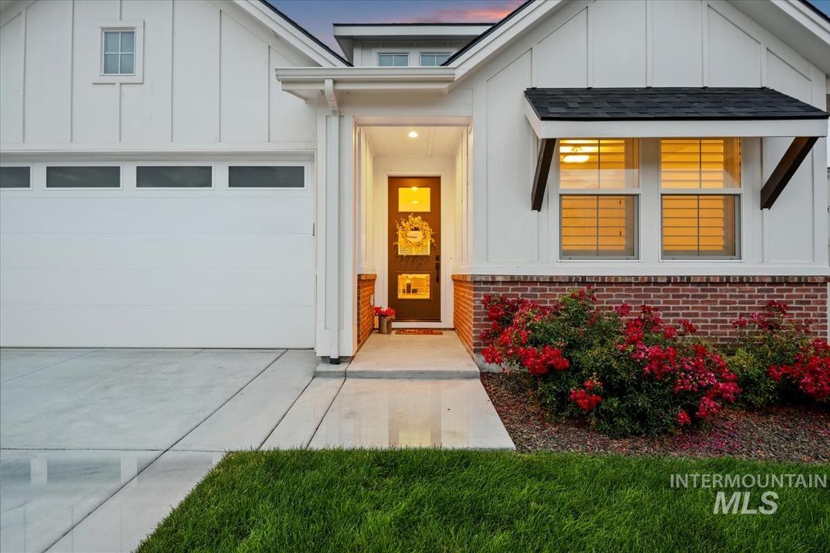 Doorway to property with board and batten siding, brick siding, and driveway