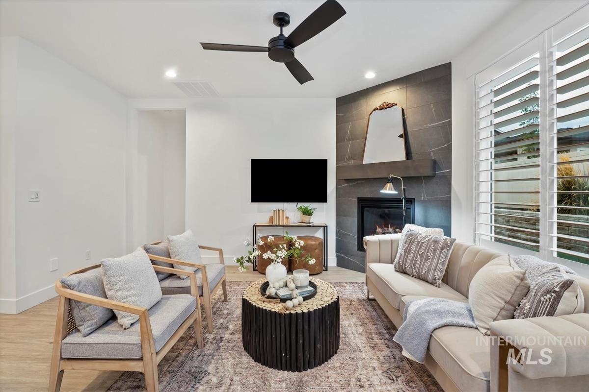 Living room featuring wood finished floors, a tiled fireplace, recessed lighting, and ceiling fan