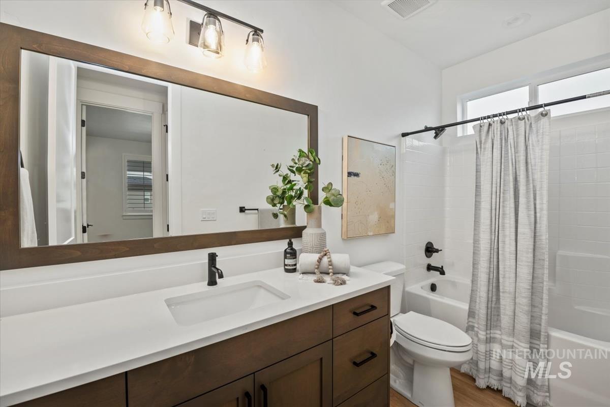 Bathroom with shower / tub combo, vanity, and light wood-type flooring