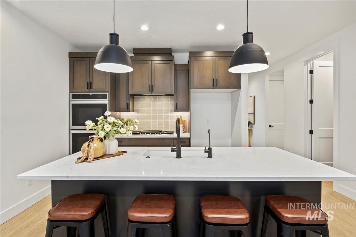Kitchen with backsplash, light wood finished floors, a breakfast bar, and recessed lighting
