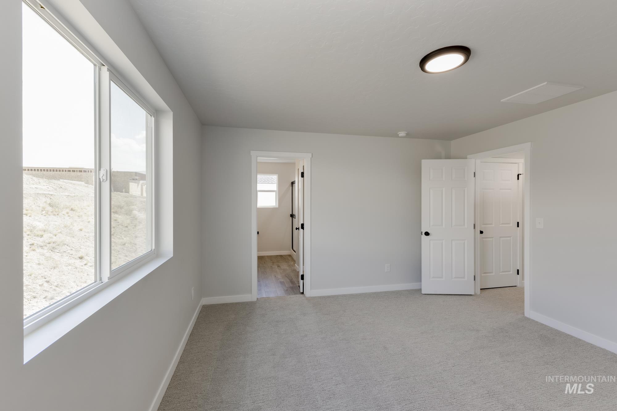 Unfurnished bedroom featuring light carpet and baseboards