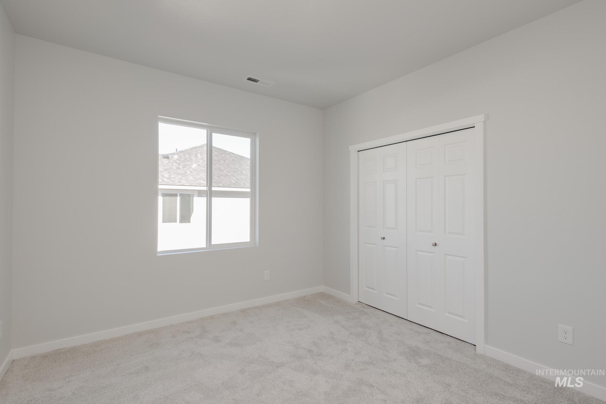 Unfurnished bedroom with light carpet and a closet