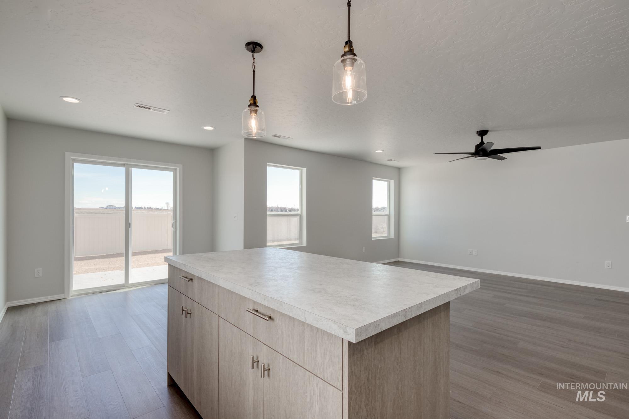 Kitchen with open floor plan, dark wood finished floors, light countertops, pendant lighting, and light brown cabinets