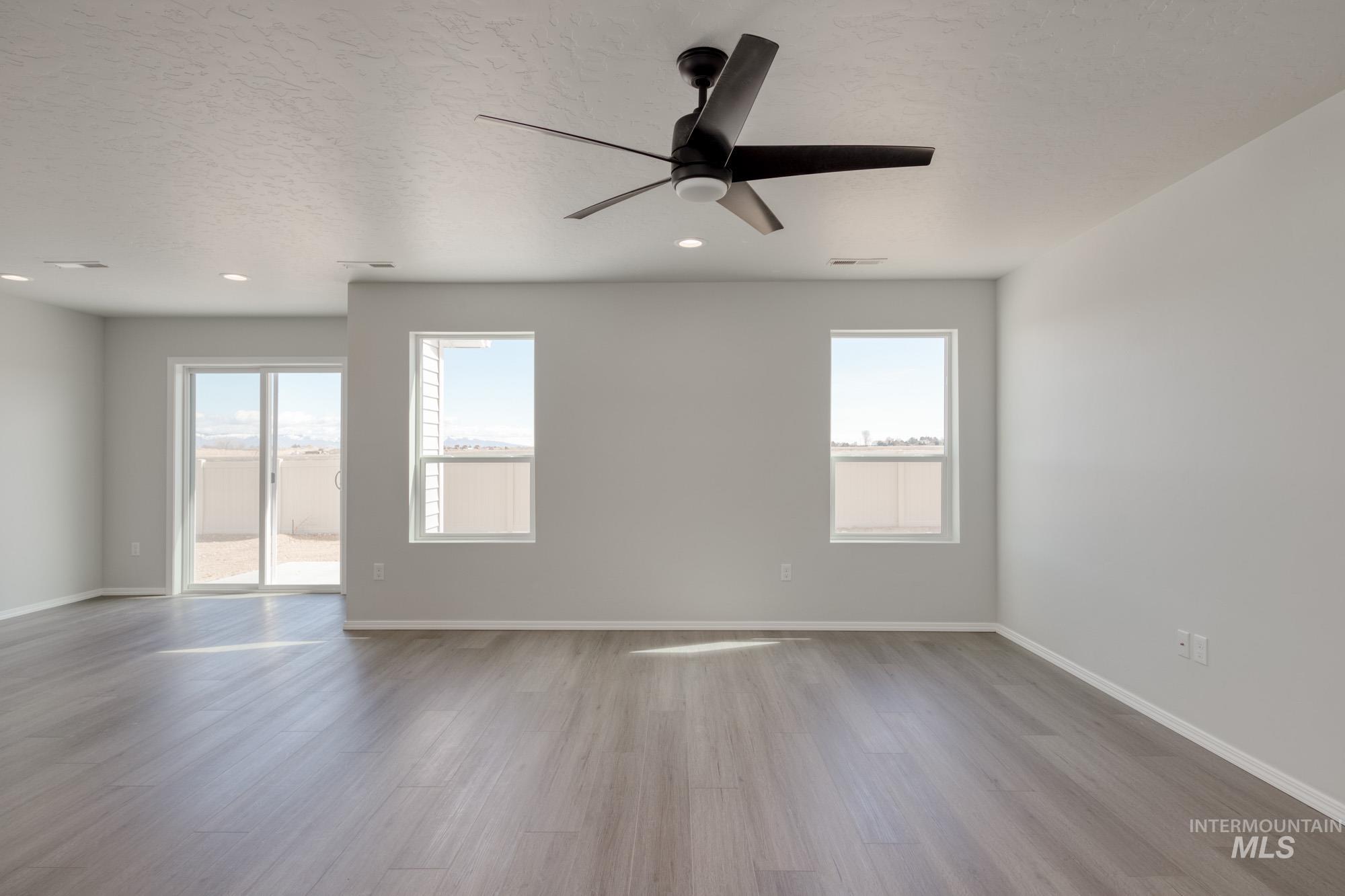 Unfurnished room featuring light wood-style flooring, a ceiling fan, a textured ceiling, plenty of natural light, and recessed lighting
