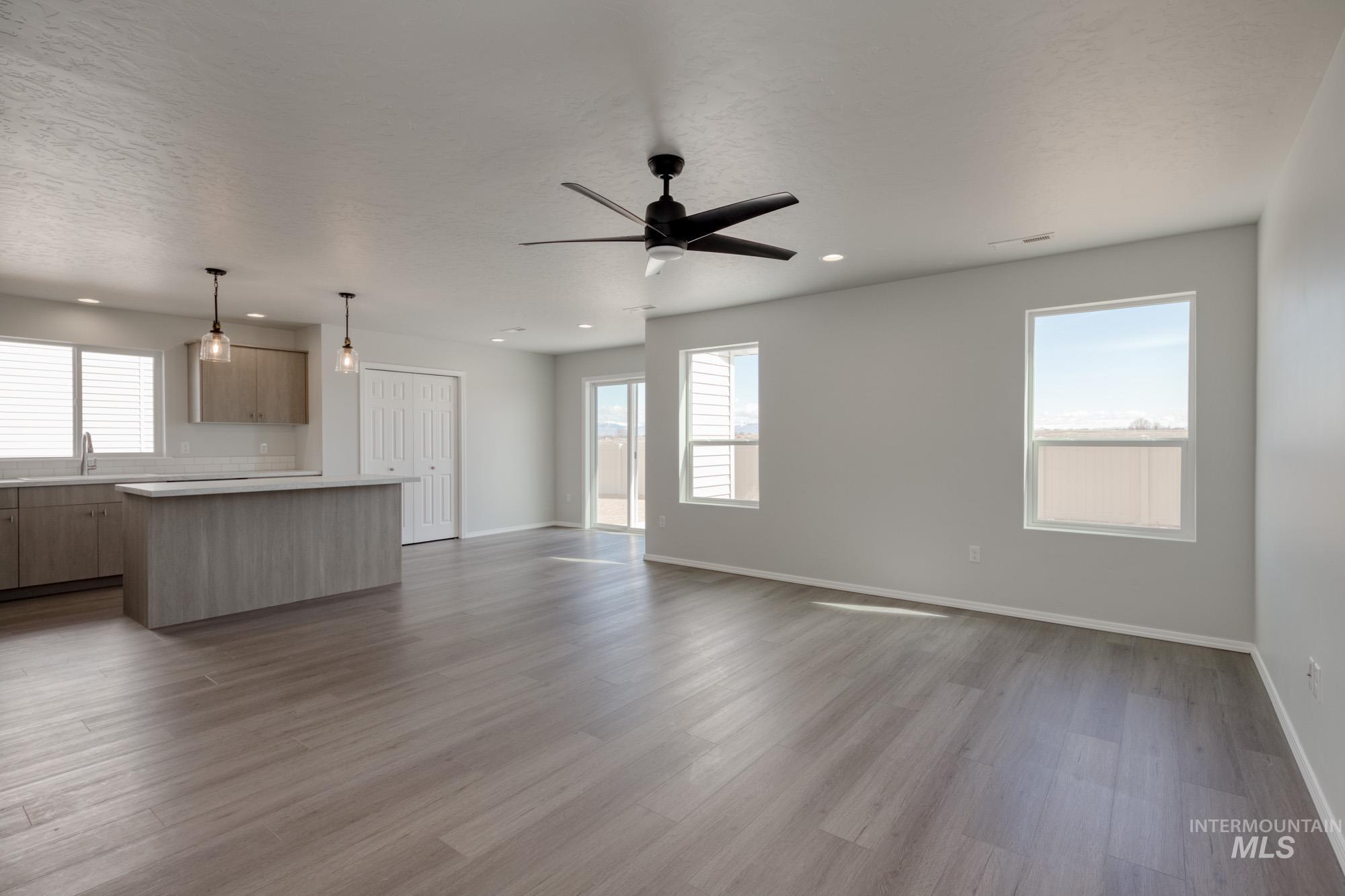 Unfurnished living room featuring dark wood-type flooring, ceiling fan, a textured ceiling, and recessed lighting