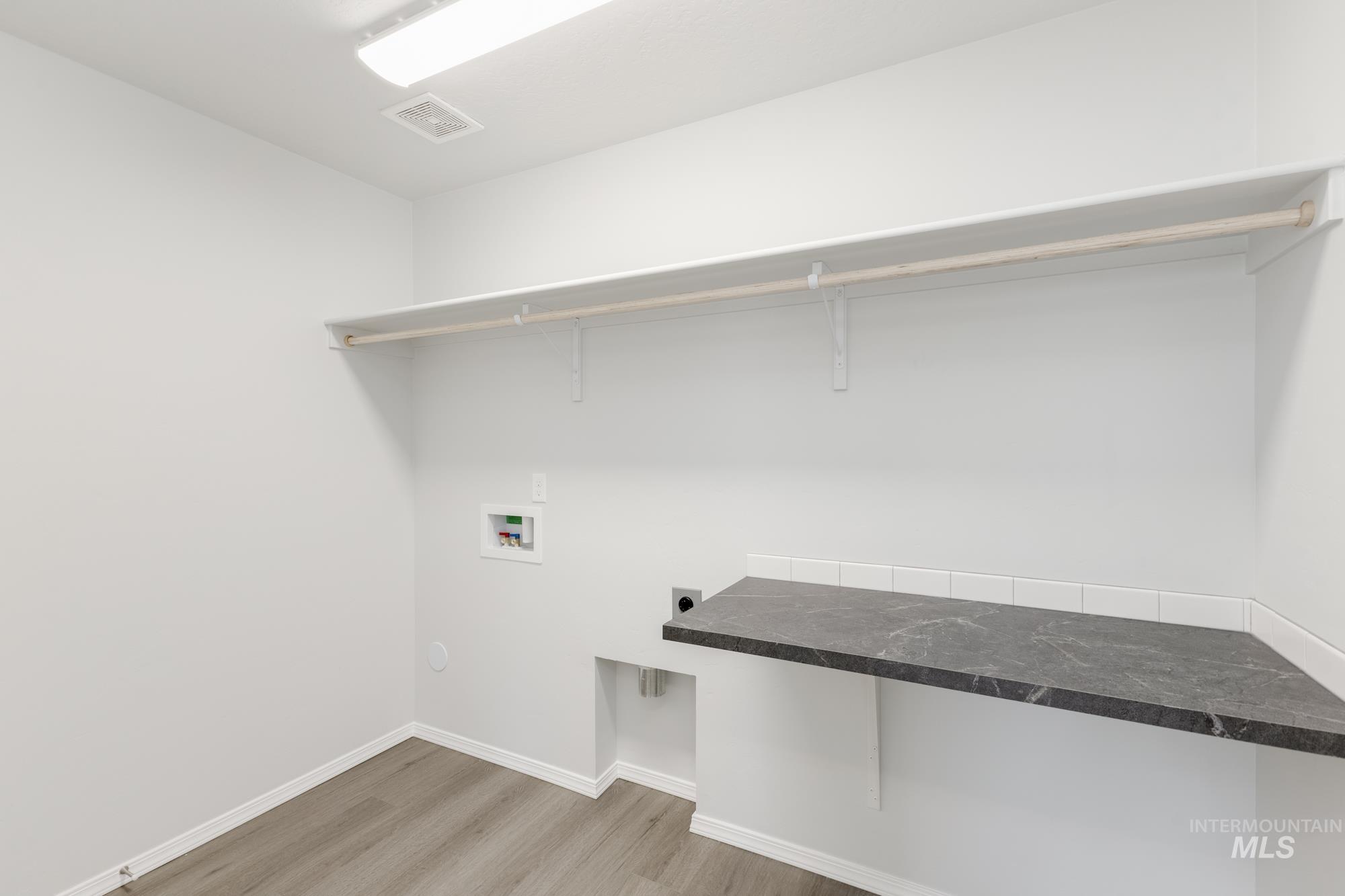 Washroom with light wood-style floors, electric dryer hookup, and hookup for a washing machine