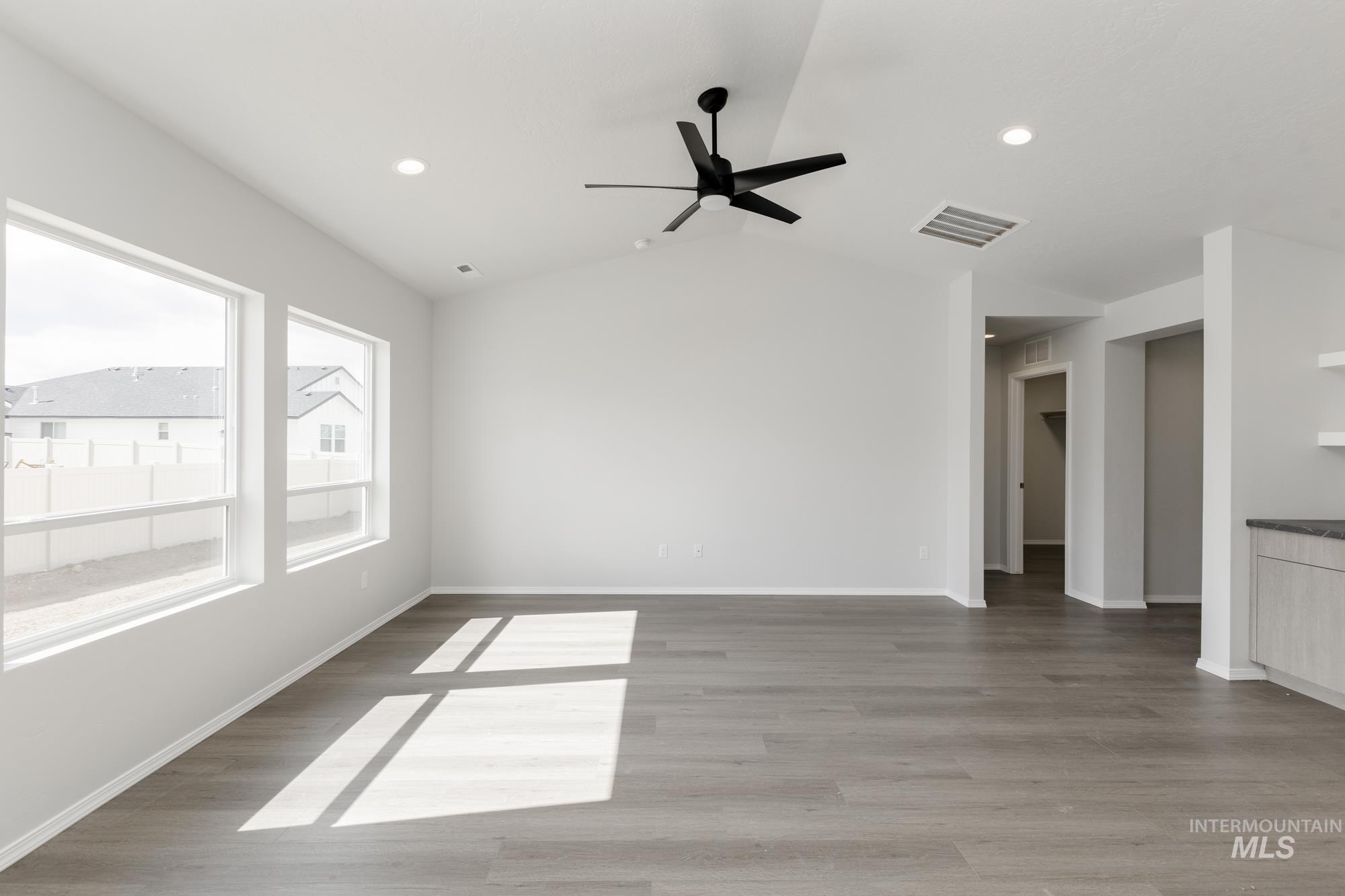 Empty room with light wood-type flooring, vaulted ceiling, ceiling fan, and recessed lighting