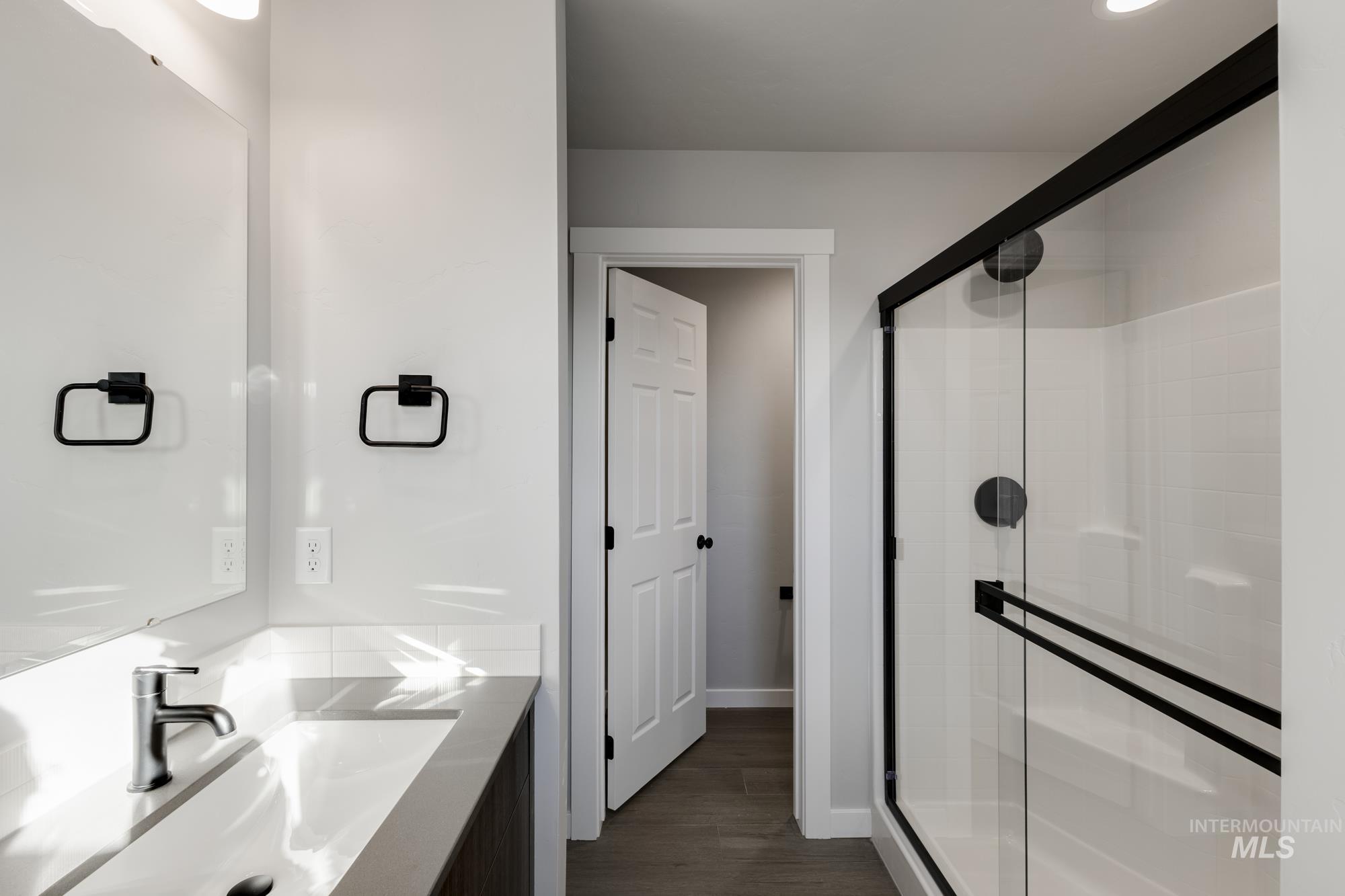 Bathroom featuring vanity, a shower stall, and dark wood-type flooring